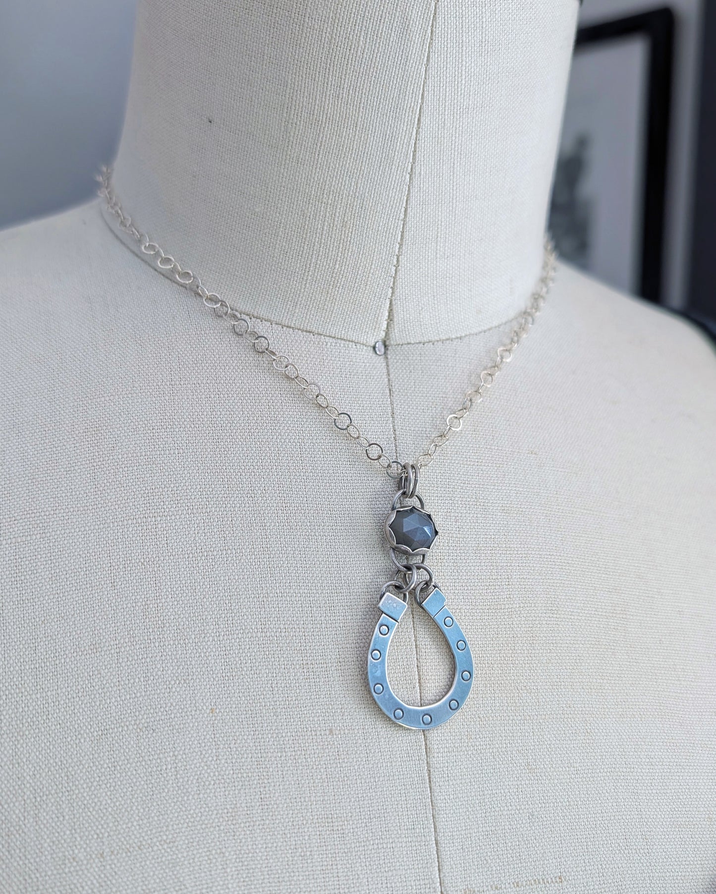 Sterling silver horseshoe necklace with gray moonstone on a mannequin close up view.