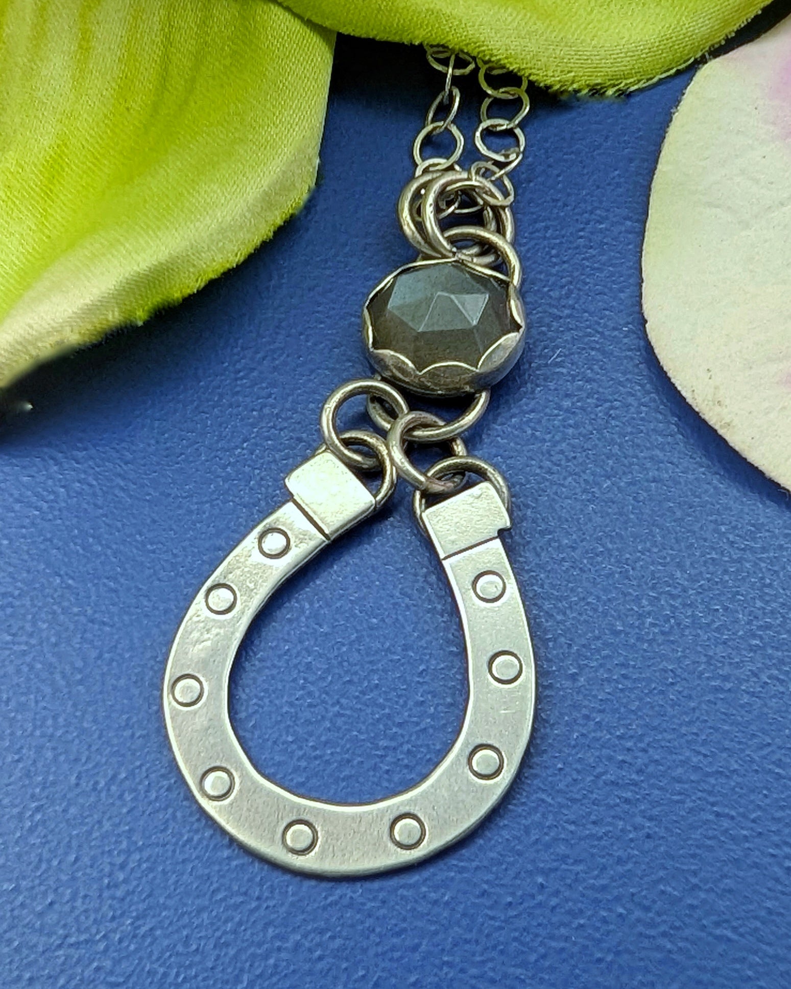 Lucky horseshoe necklace with grey moonstone on a blue background