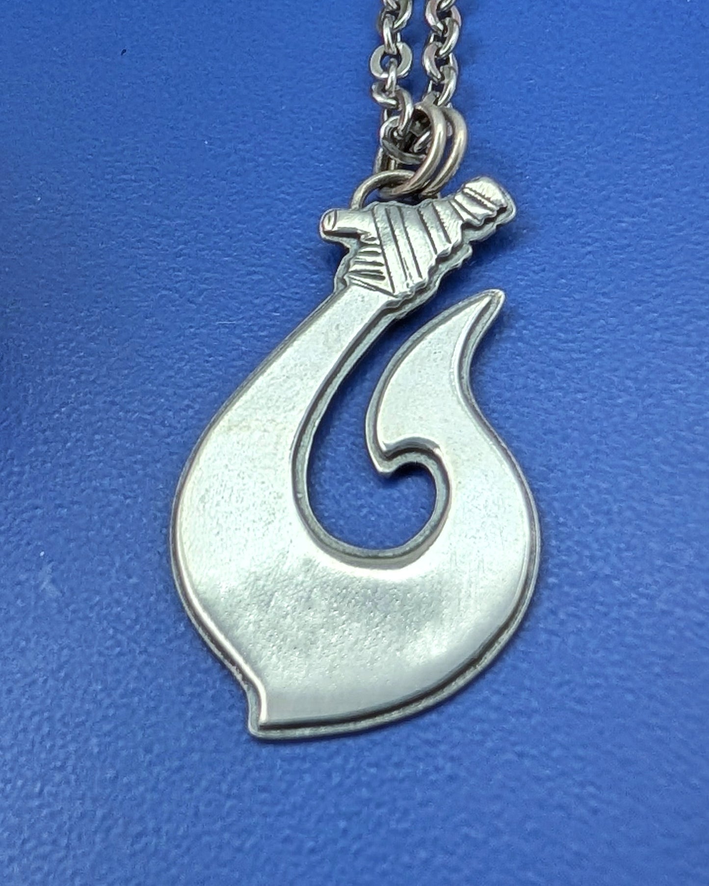 Hawaiian fish hook necklace on a blue background
