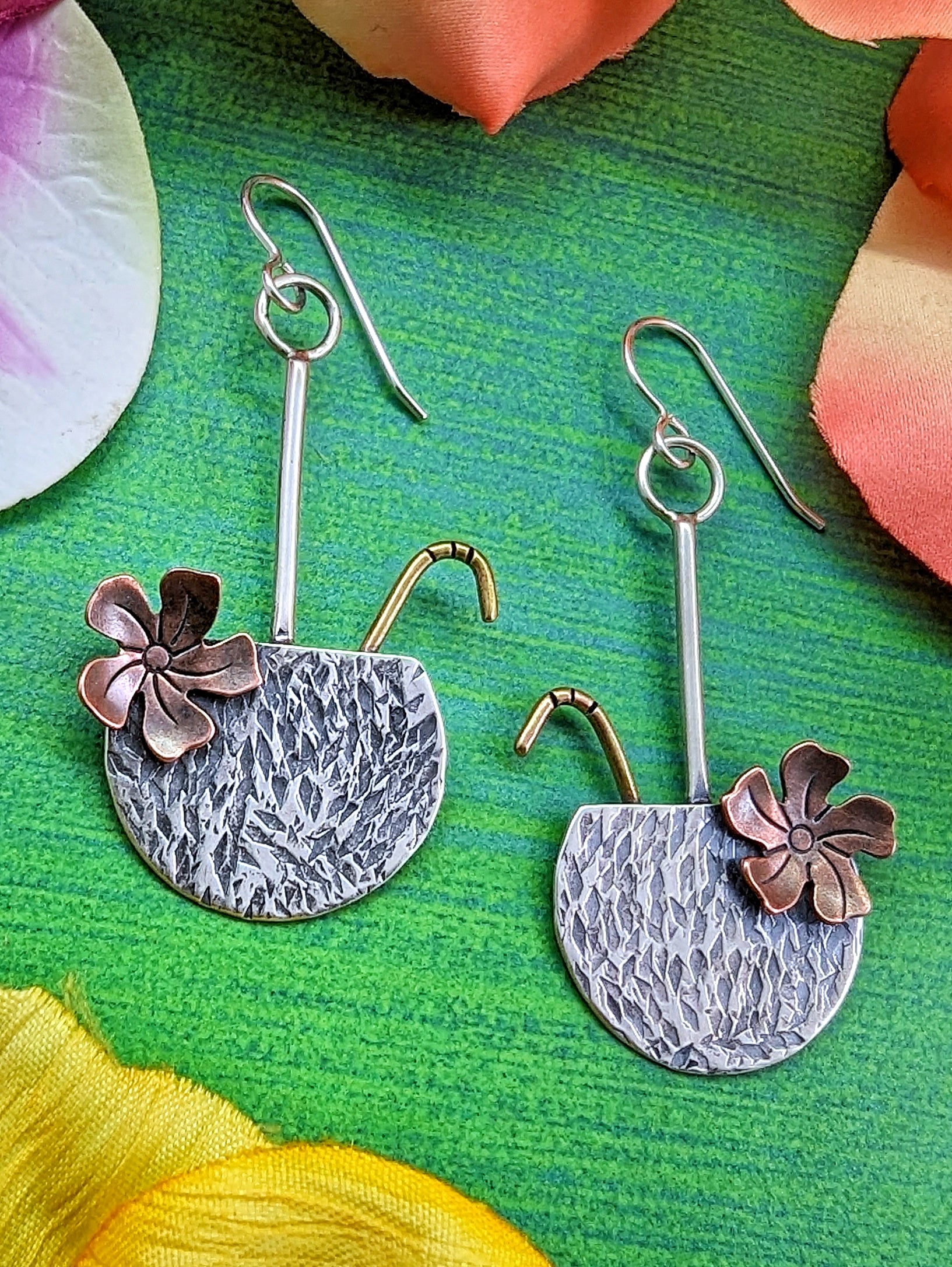 Coconut drop earrings in sterling silver with brass straw and copper flower on a green background.