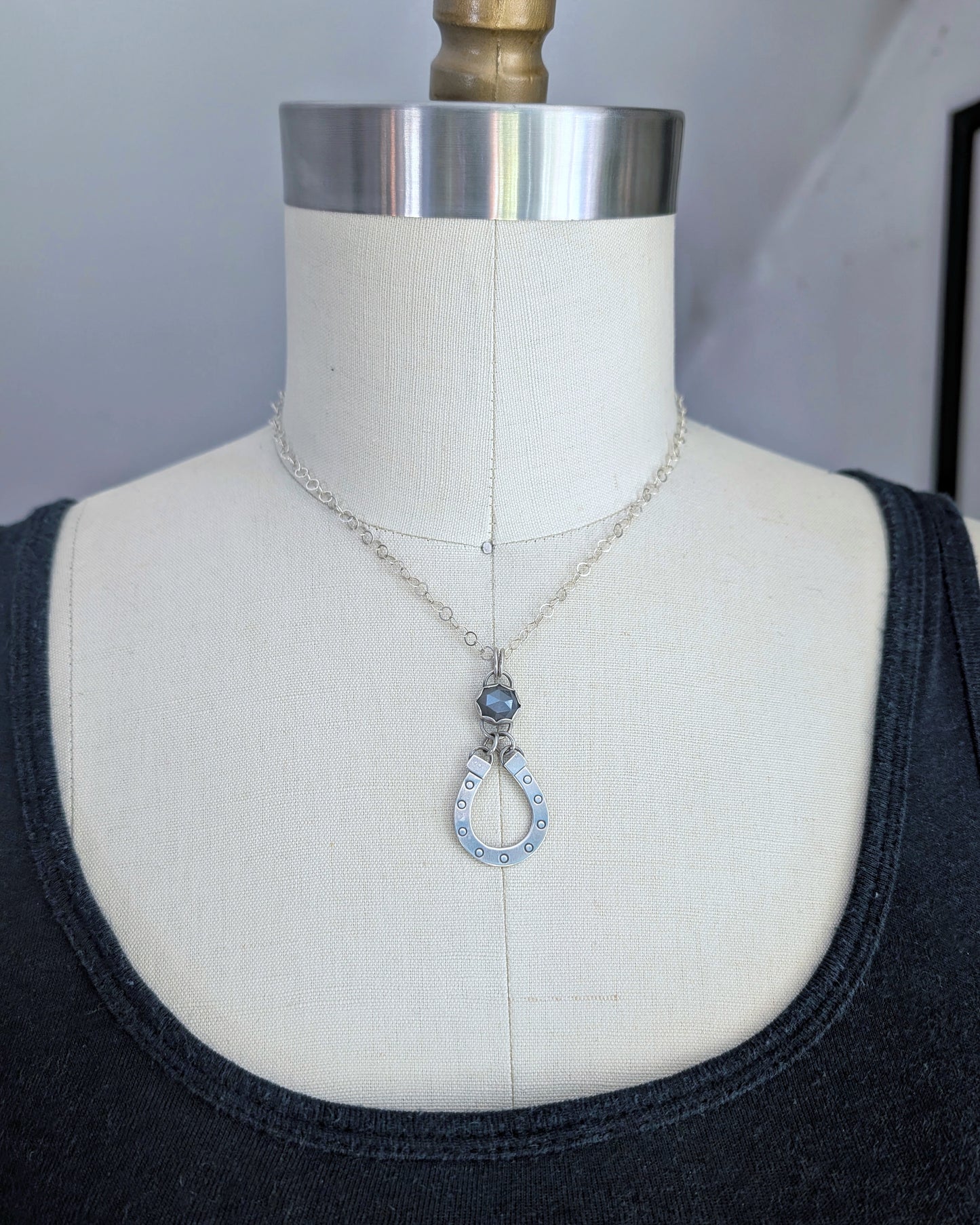 Sterling silver horseshoe necklace with gray moonstone on a mannequin