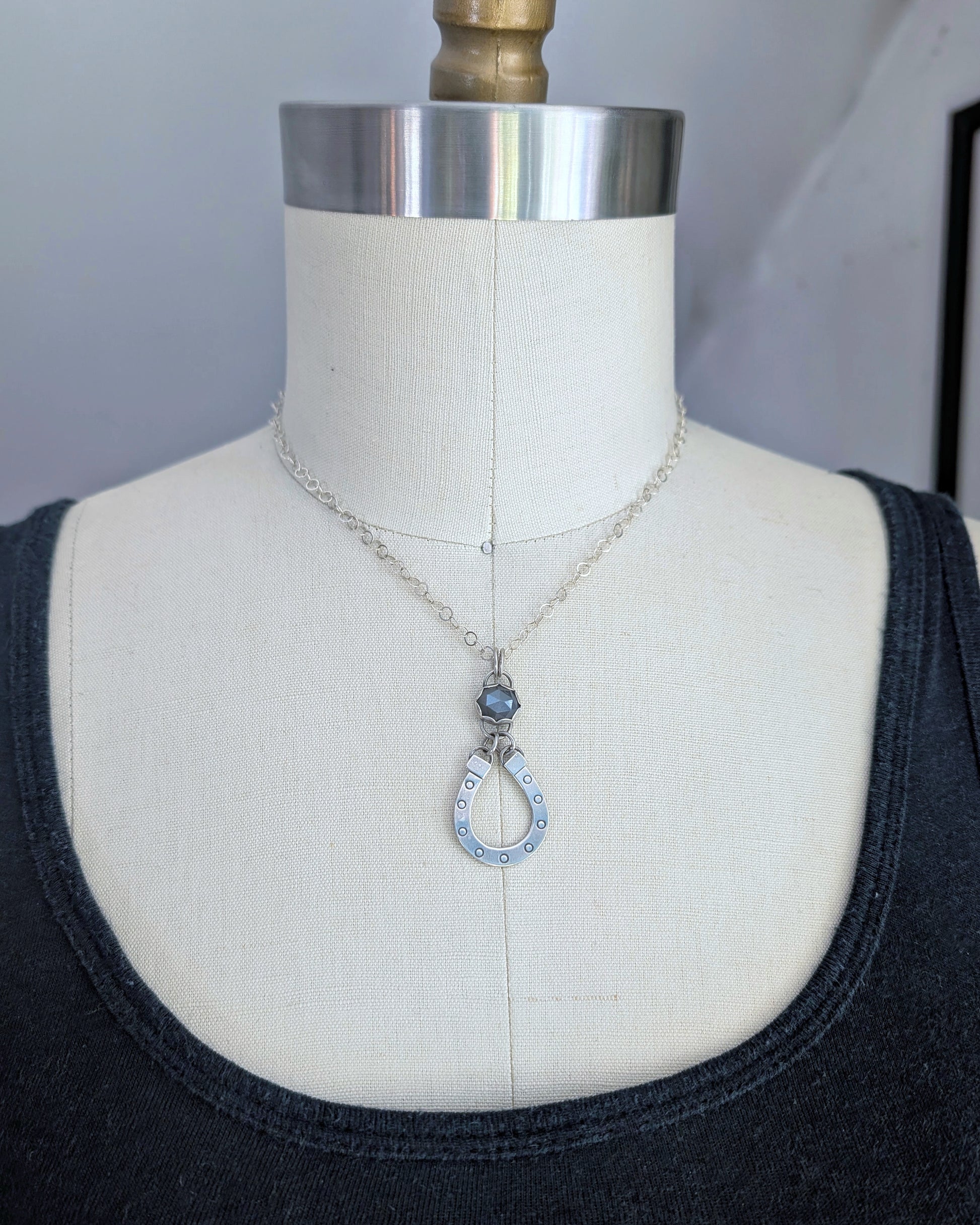 Sterling silver horseshoe necklace with gray moonstone on a mannequin