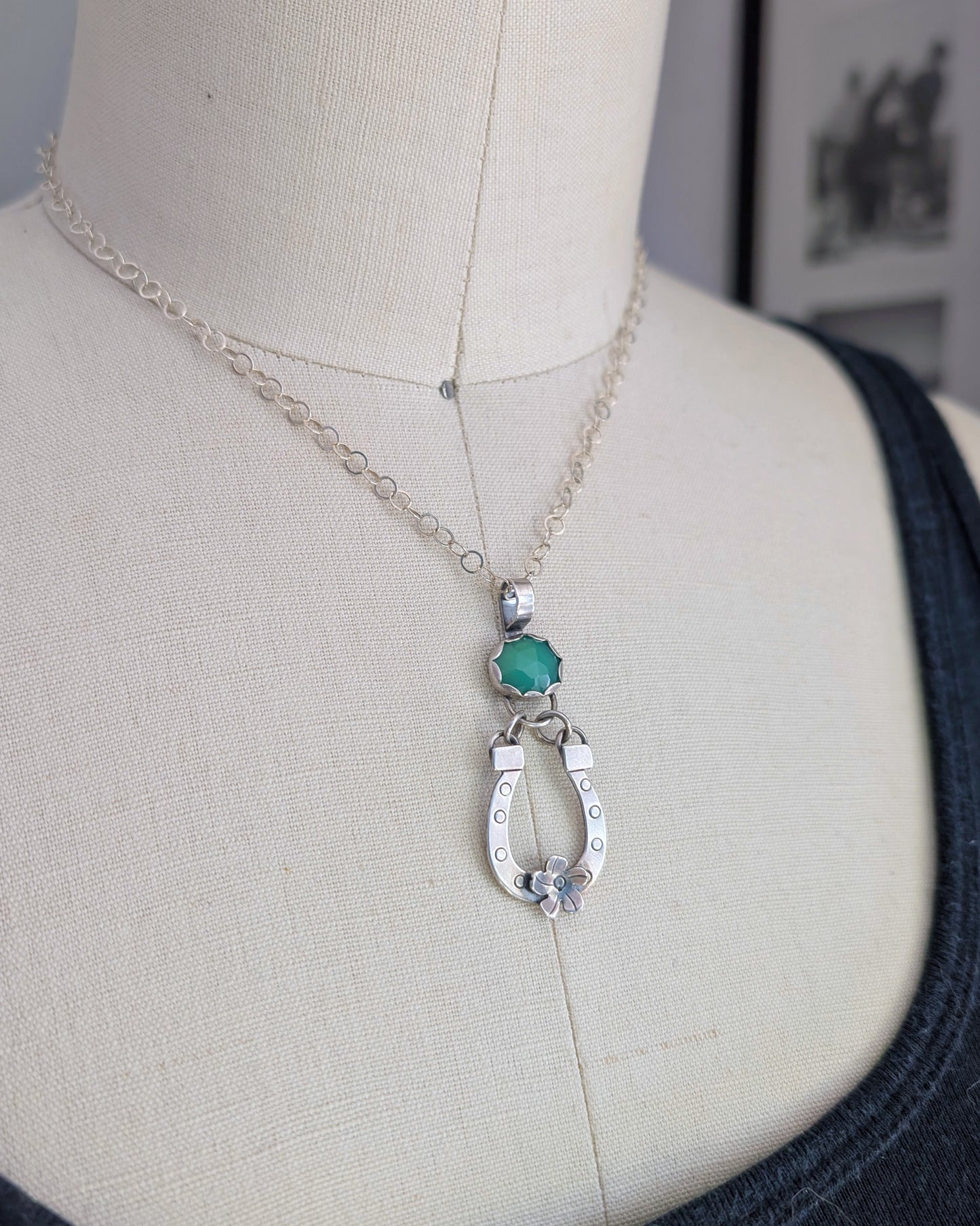 Necklace with a horseshoe and green chrysoprase stone on a mannequin.