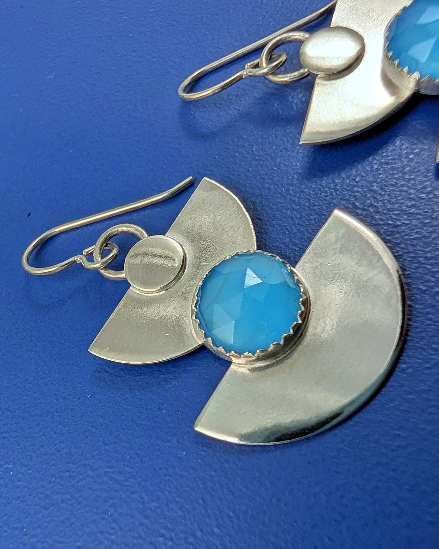Close up of sterling silver half moon earrings with blue chalcedony