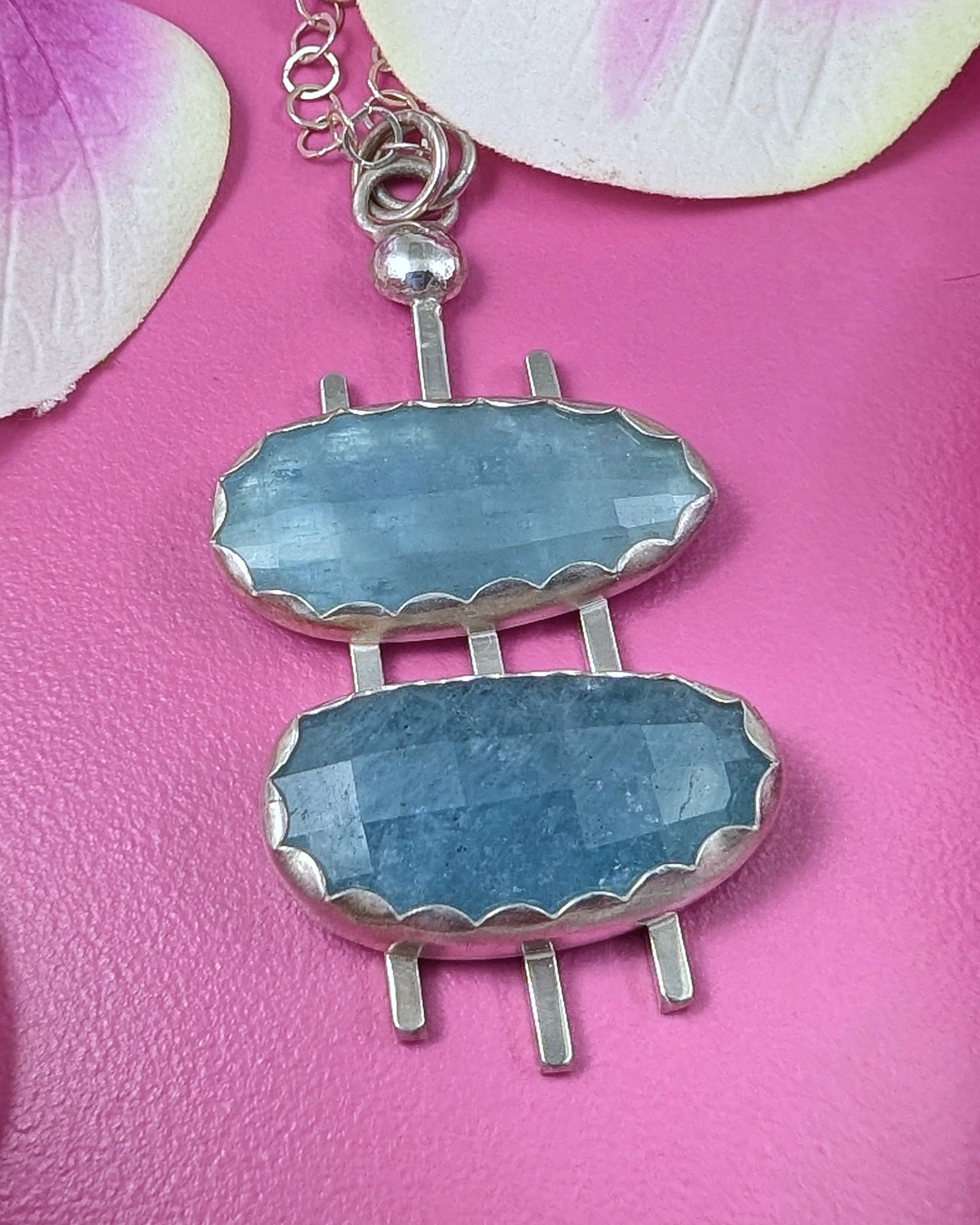 ouble decker oval necklace in sterling silver with rosecut aquamarine stones on a pink background