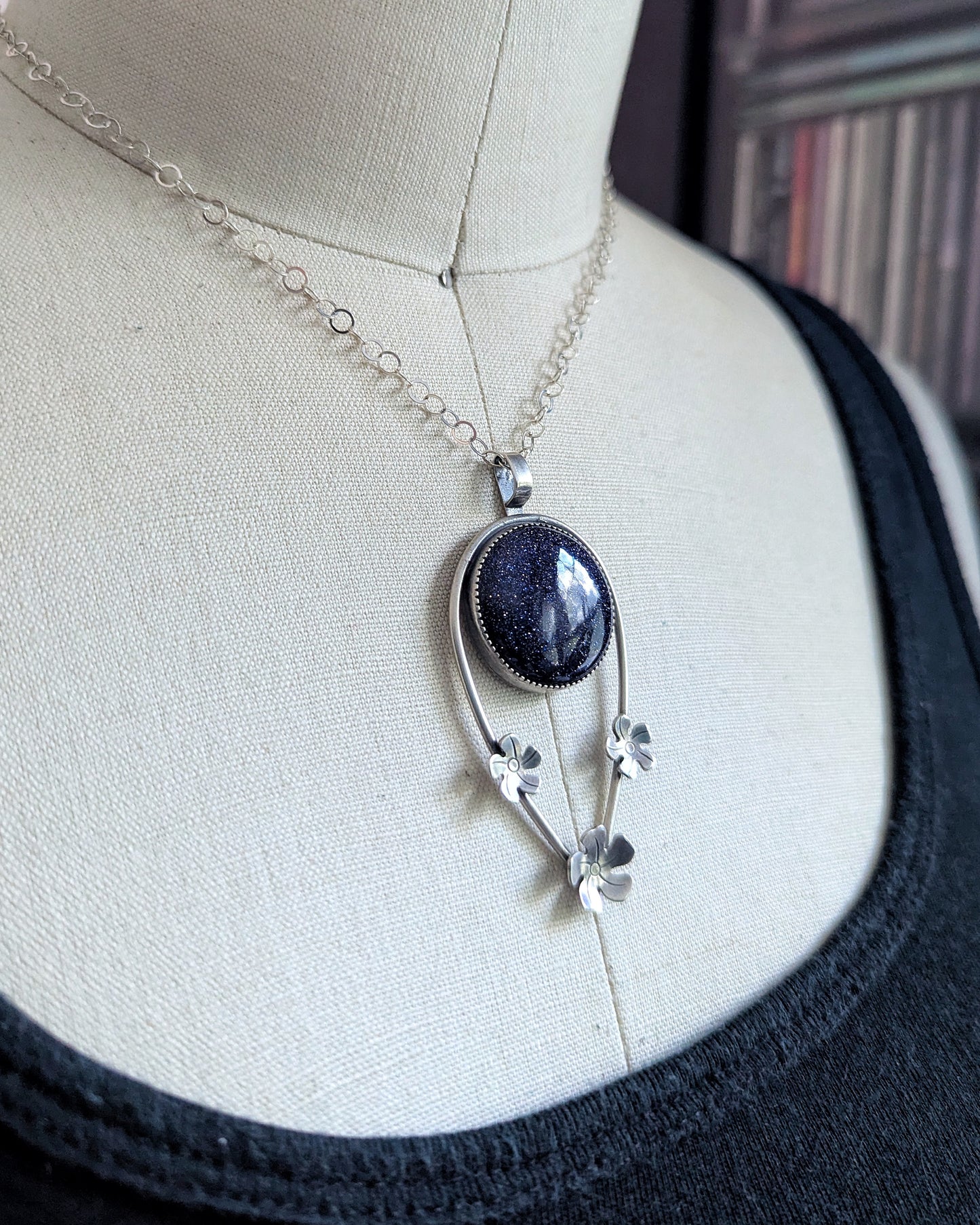 Tiki lover necklace featuring blue goldstone and sterling silver flowers