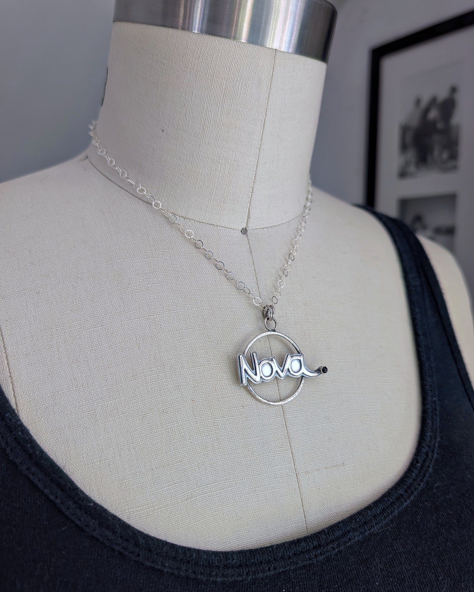 Silver necklace with 'Nova' pendant on a mannequin bust.