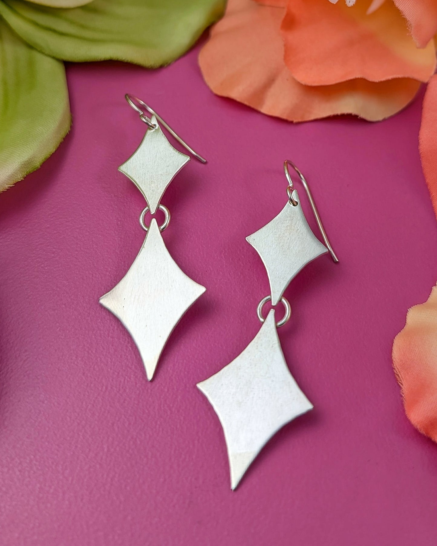 Sterling silver retro diamond earrings on a pink background