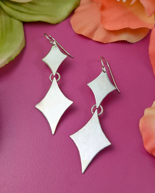 Sterling silver retro diamond earrings on a pink background