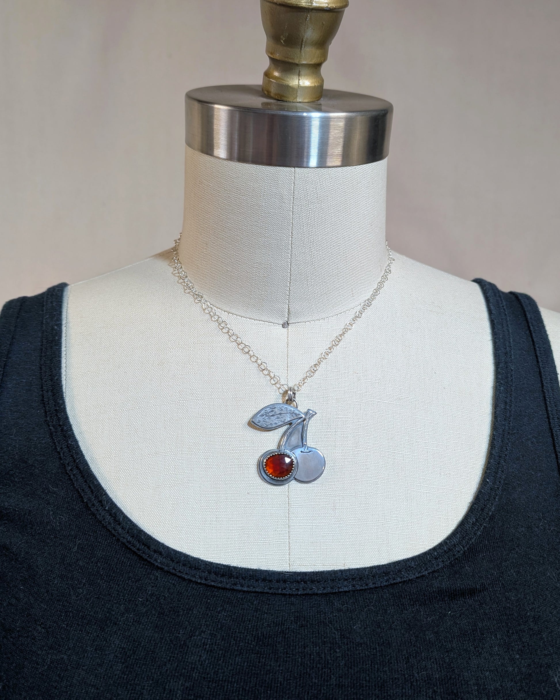 Sterling silver cherries necklace with rosecut red garnet on a dress form