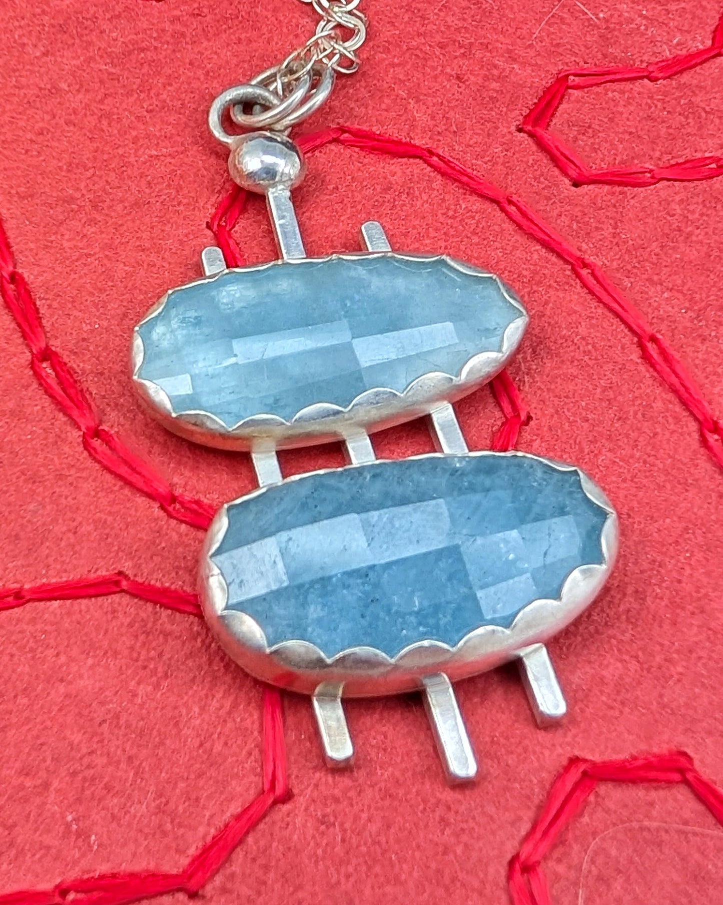 ouble decker oval necklace in sterling silver with rosecut aquamarine stones on a red background