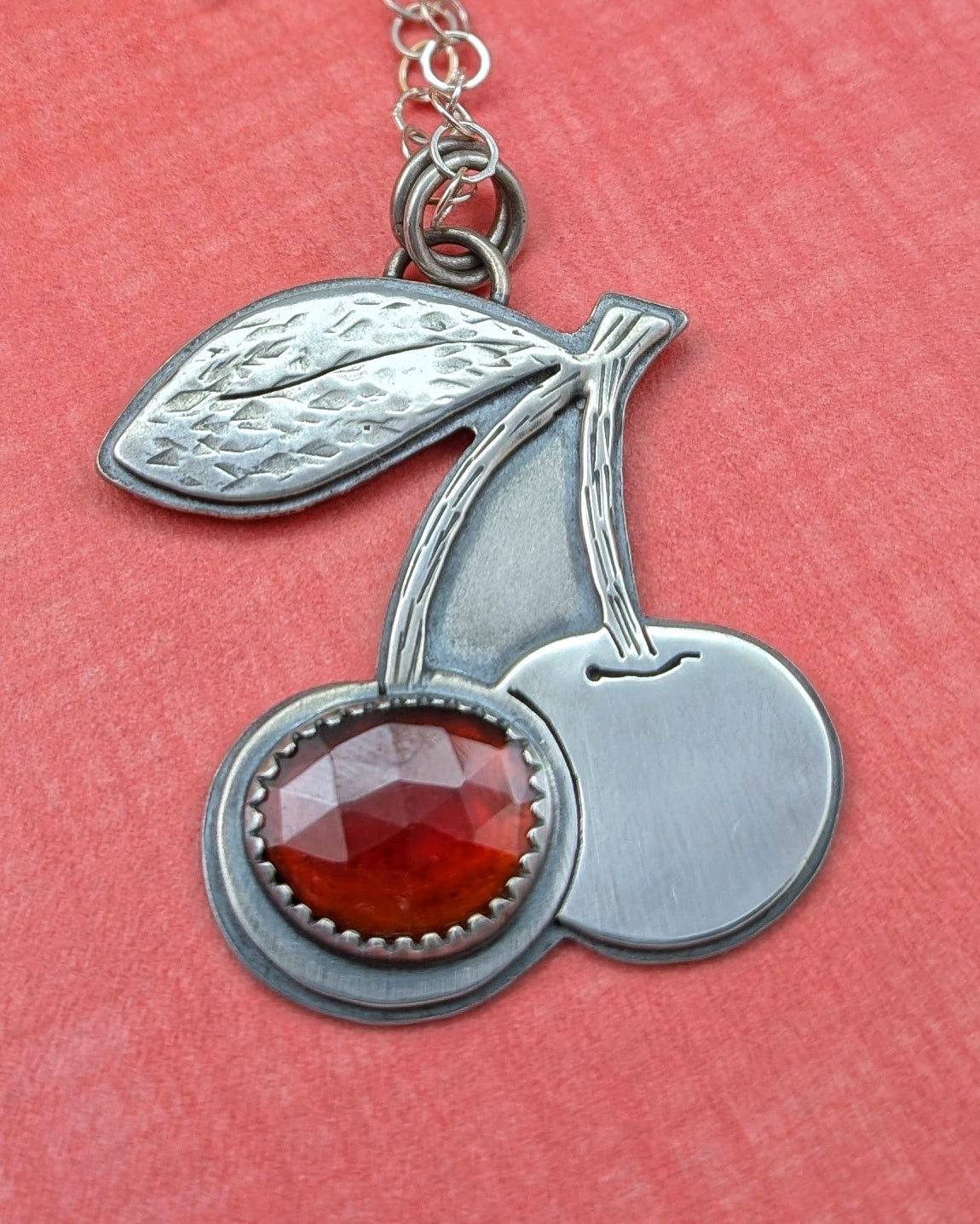 Sterling silver cherries necklace with rosecut red garnet on a peach background