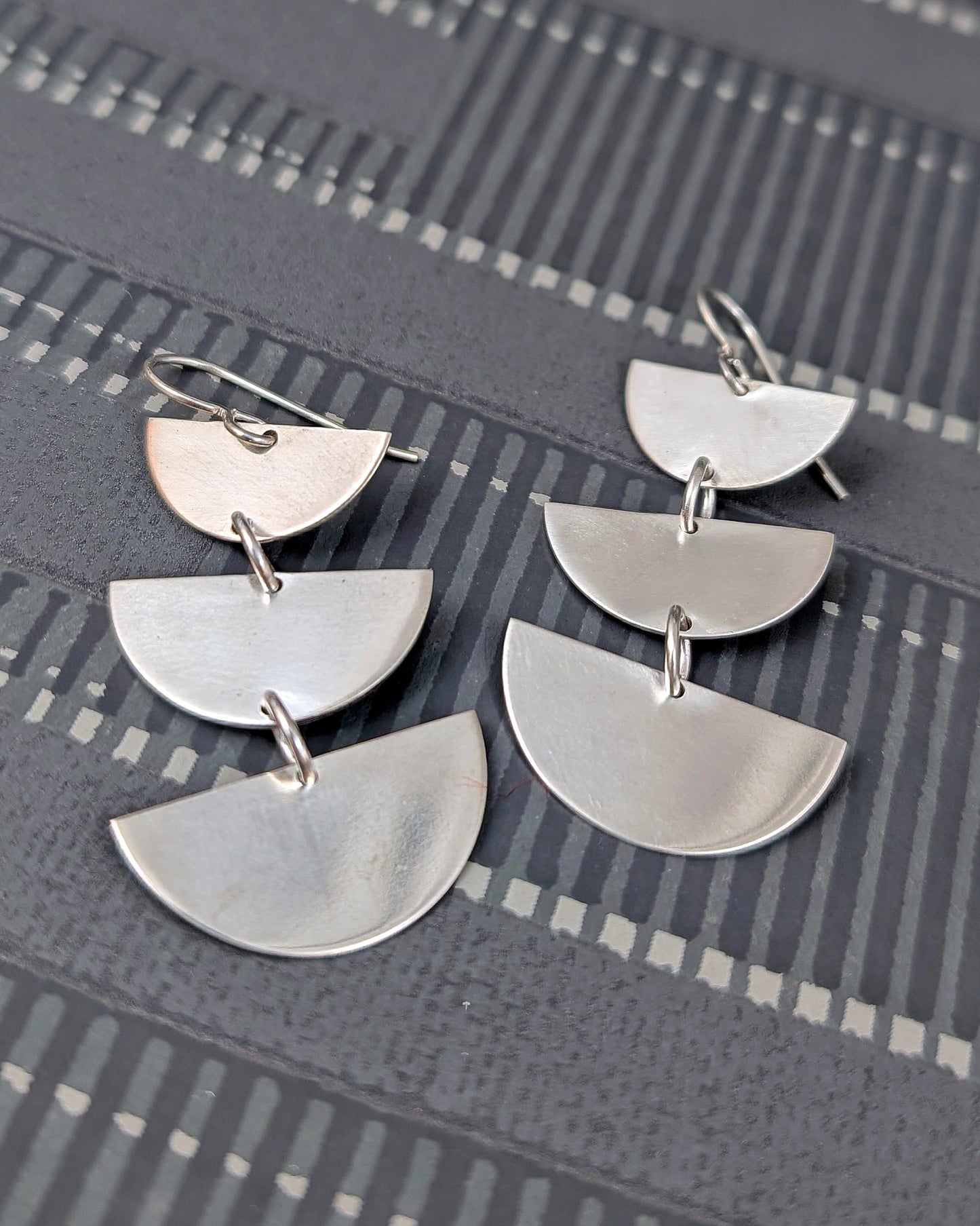 Sterling silver half moon dangle earrings on a black background