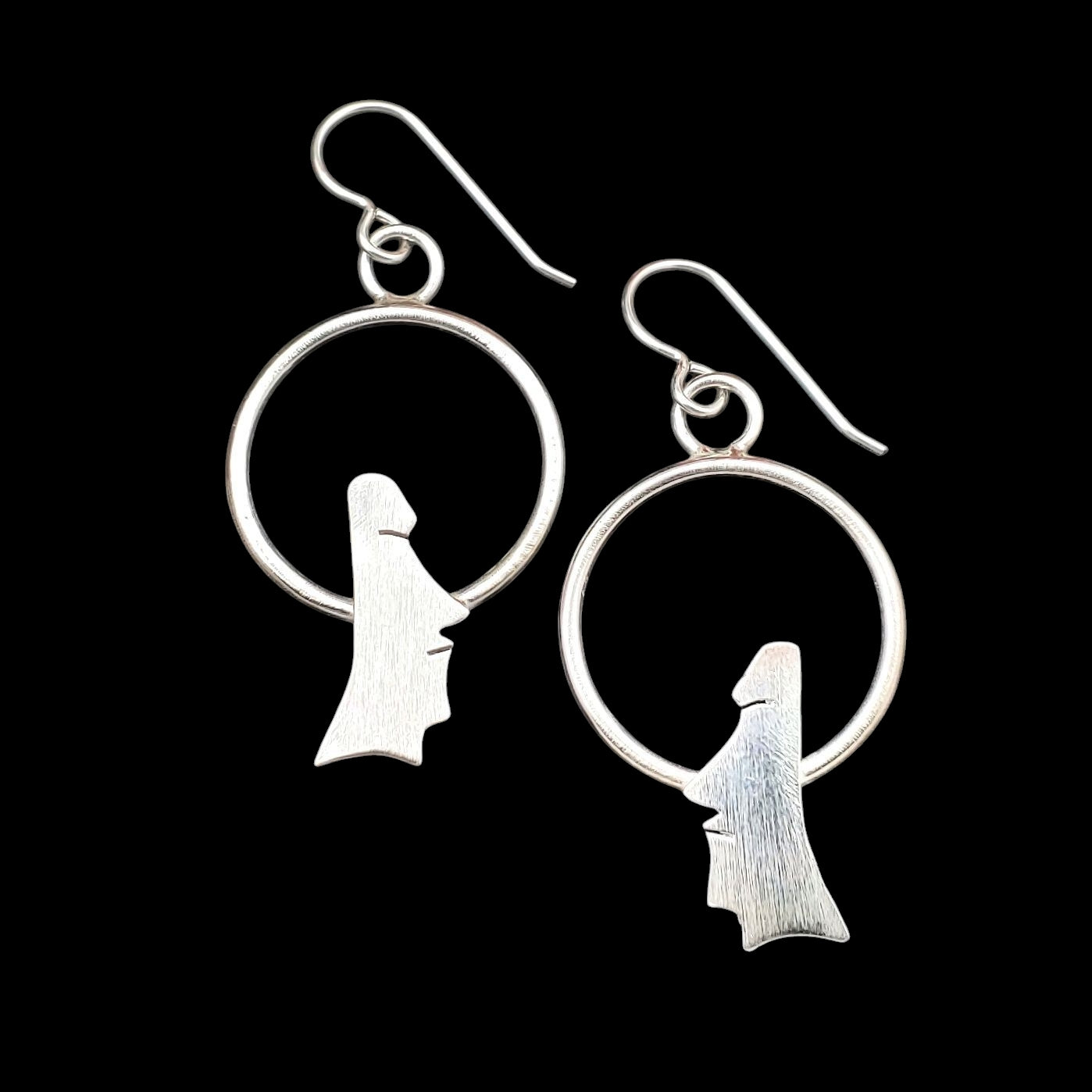 Handmade sterling silver moai earrings on circles.