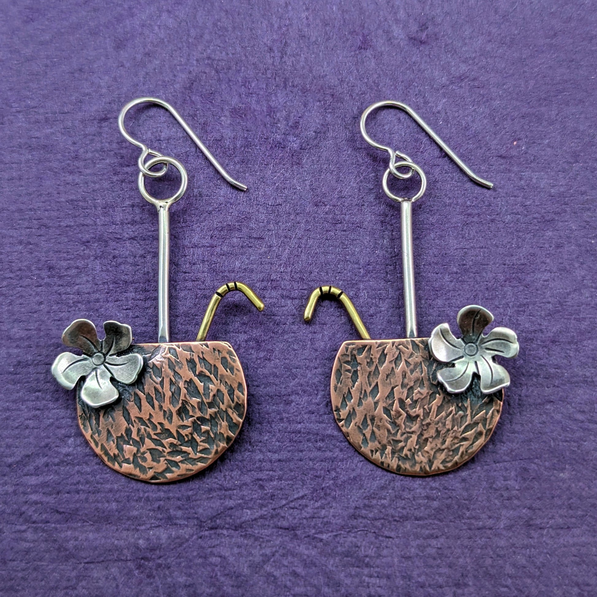 Copper coconut drop earrings with brass straw and sterling silver flower on a purple background