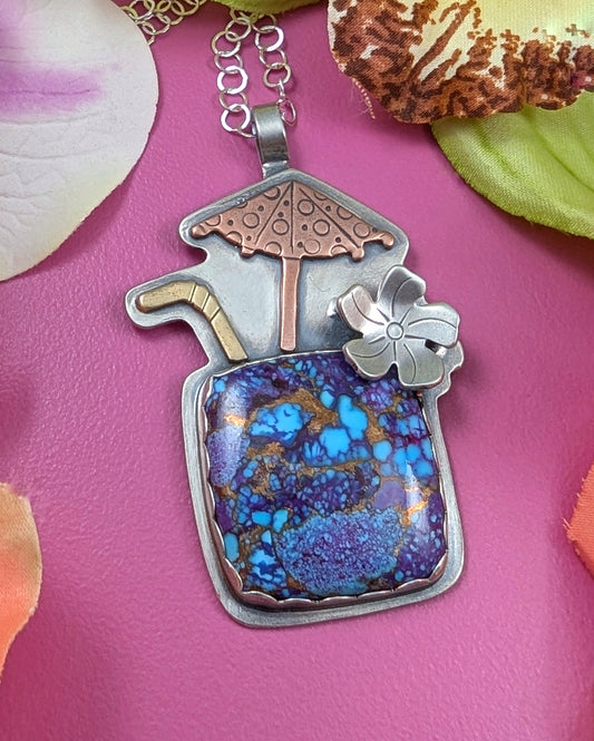 Purple copper turquoise tiki drink necklace on pink background with flowers