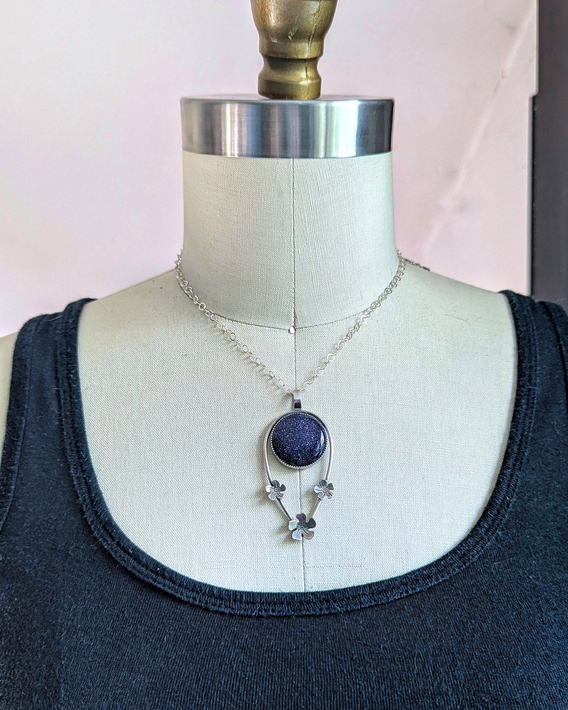 The tiki flower necklace with blue goldstone on dress form