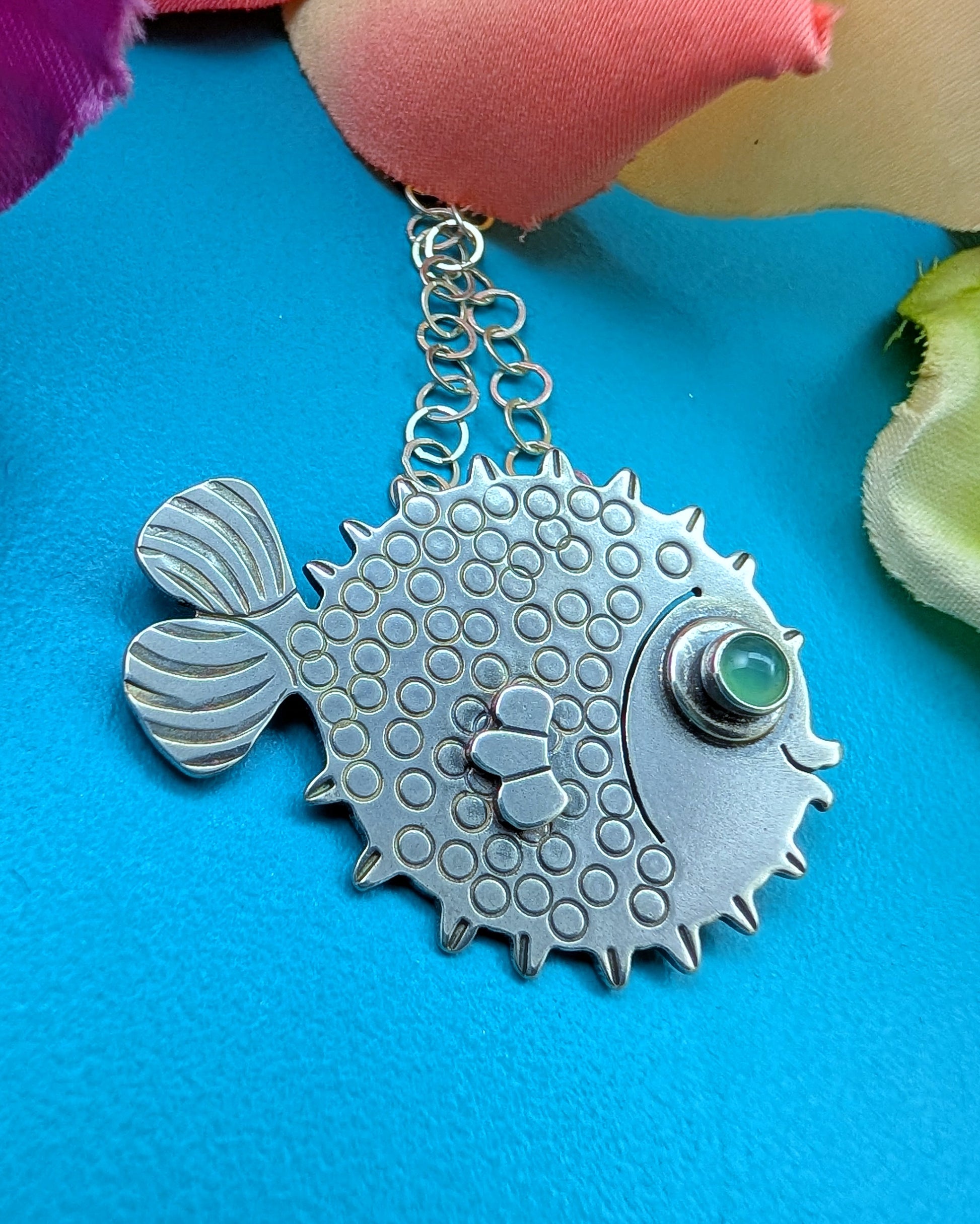 Sterling silver puffer fish necklace with chrysoprase eye on turquoise background