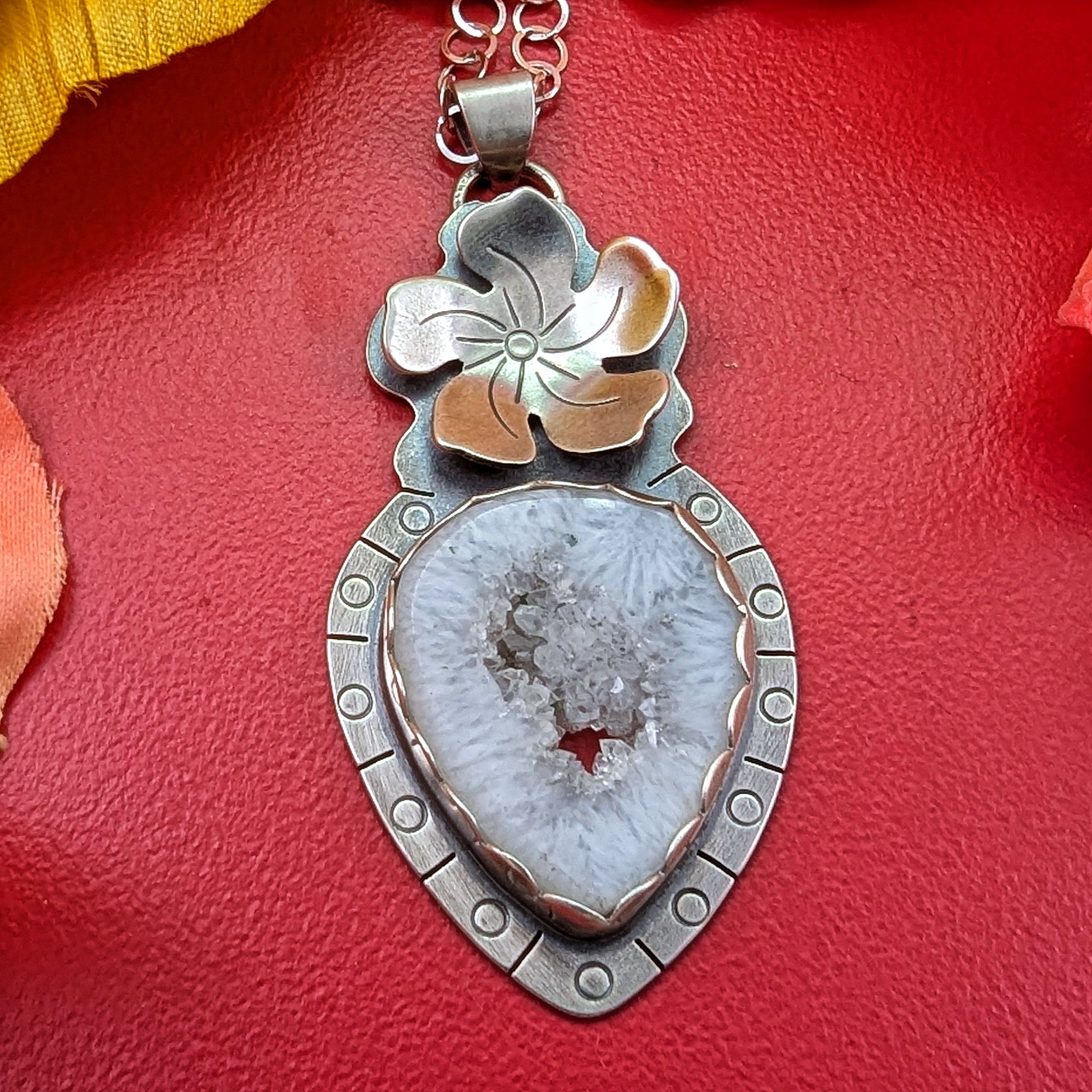 Sterling silver flower necklace with druzy quartz on a red background