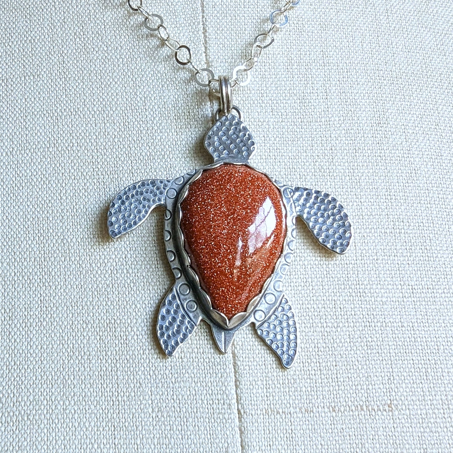 Sterling silver handmade sea turtle necklace with goldstone close up