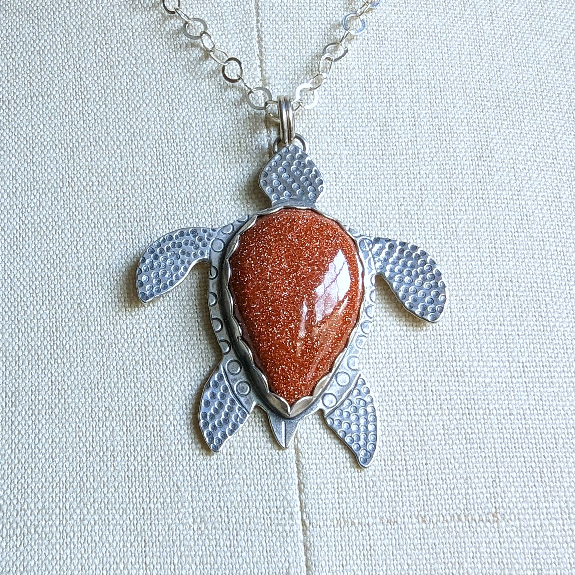 Sterling silver handmade sea turtle necklace with goldstone close up