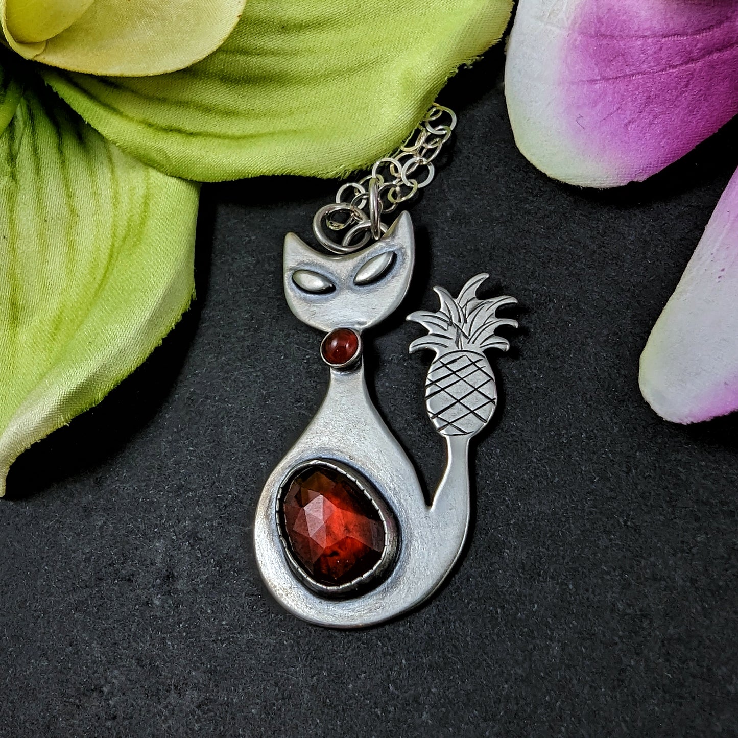 Sterling silver handmade cat with pineapple tail and garnet on black background