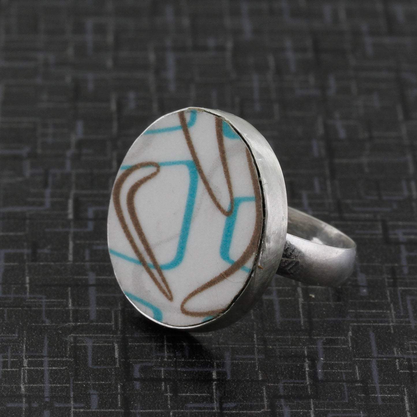 Side view of boomerang laminate ring in turquoise and brown pattern