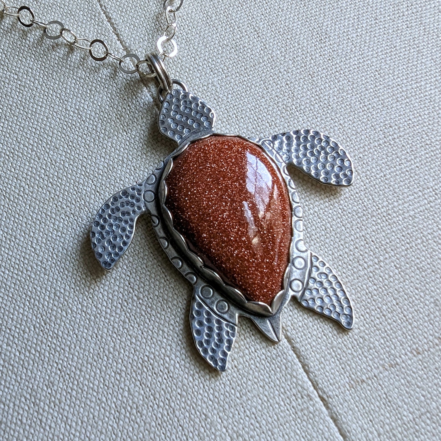 Sterling silver handmade sea turtle necklace with goldstone extreme close up