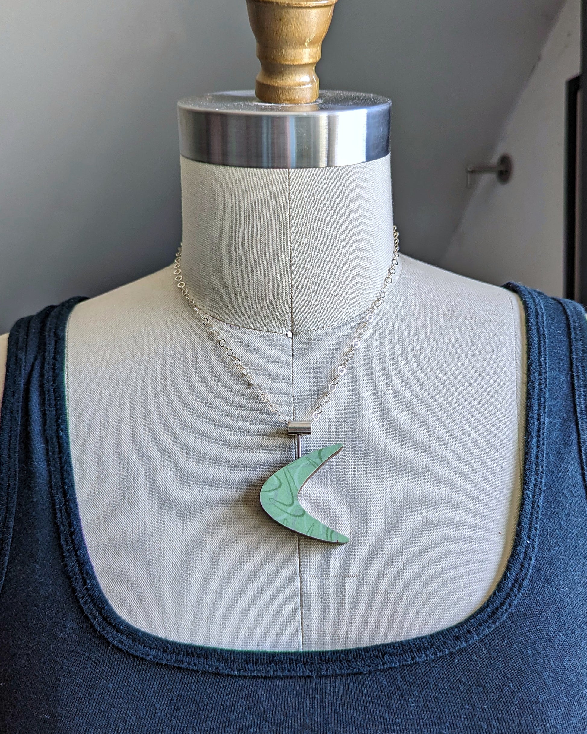 Boomerang shaped laminate on wood necklace on a dress form to see the size
