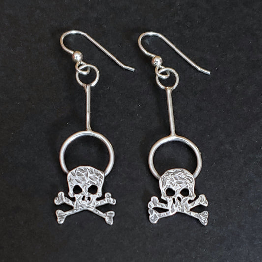 Hammered sterling silver skull dangle earrings on a black background.