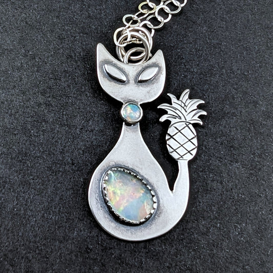Sterling silver handmade cat with pineapple tail and Ethiopian opal on a black backgroun