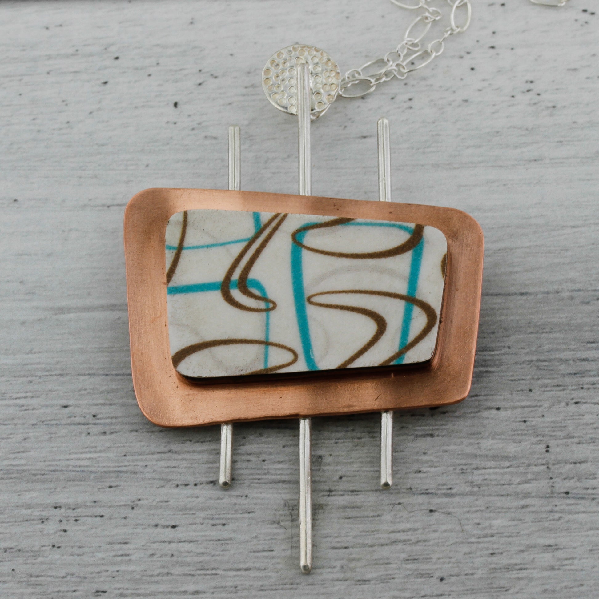 Boomerang shaped laminate in turquoise and white set on a marquee shaped pendant