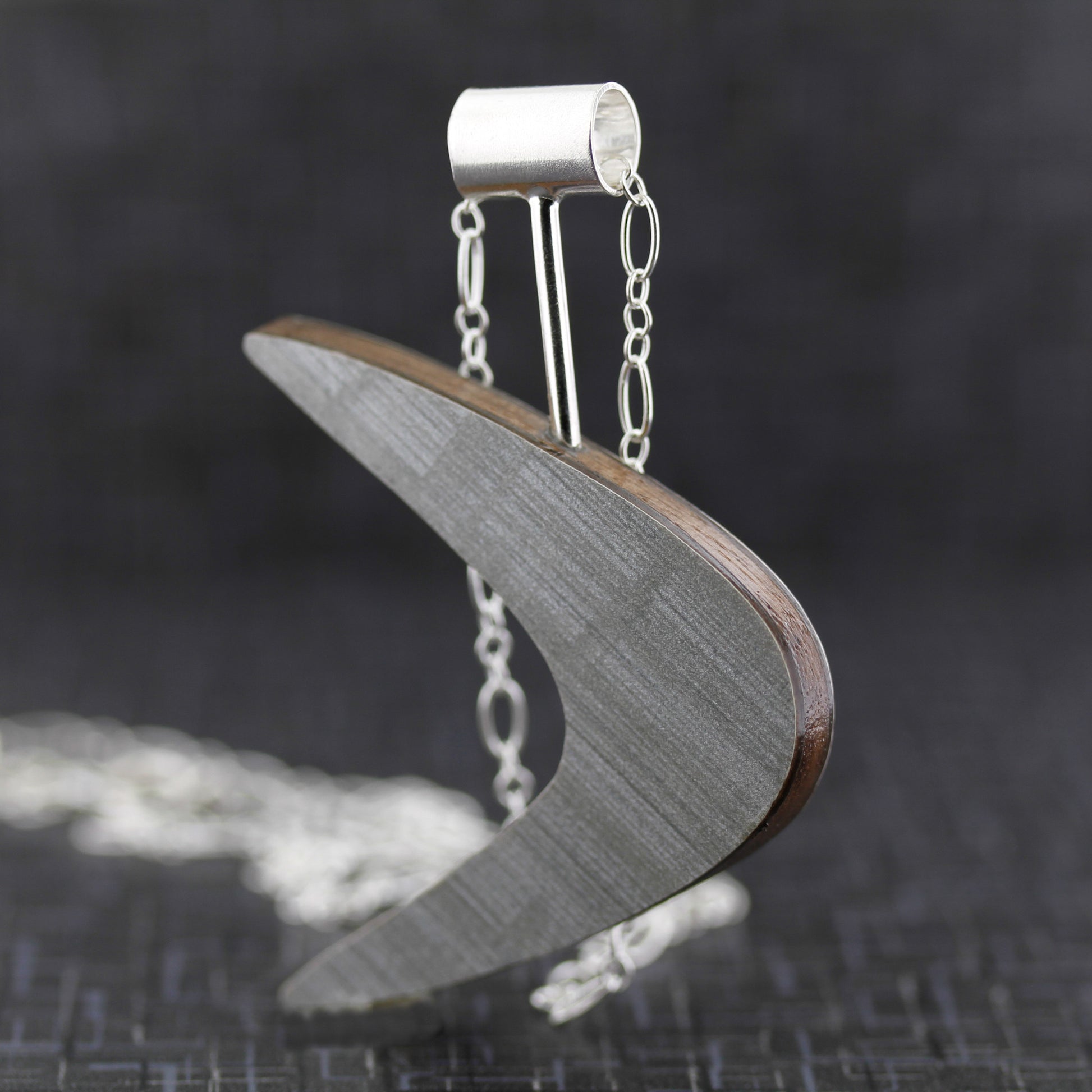 Boomerang shaped laminate on wood necklace.