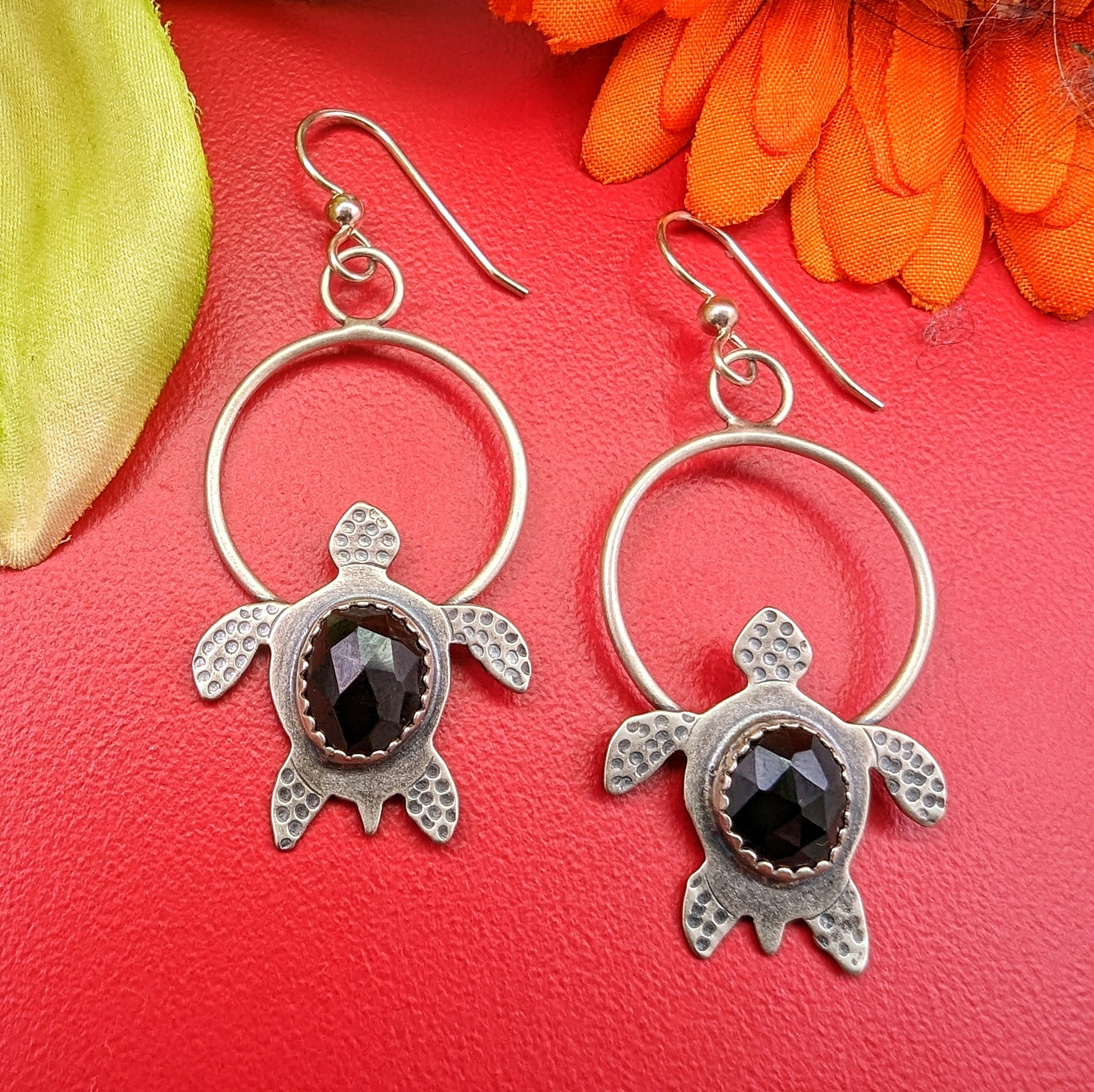 Sterling silver handmade earrings with rosecut black onyx on red background