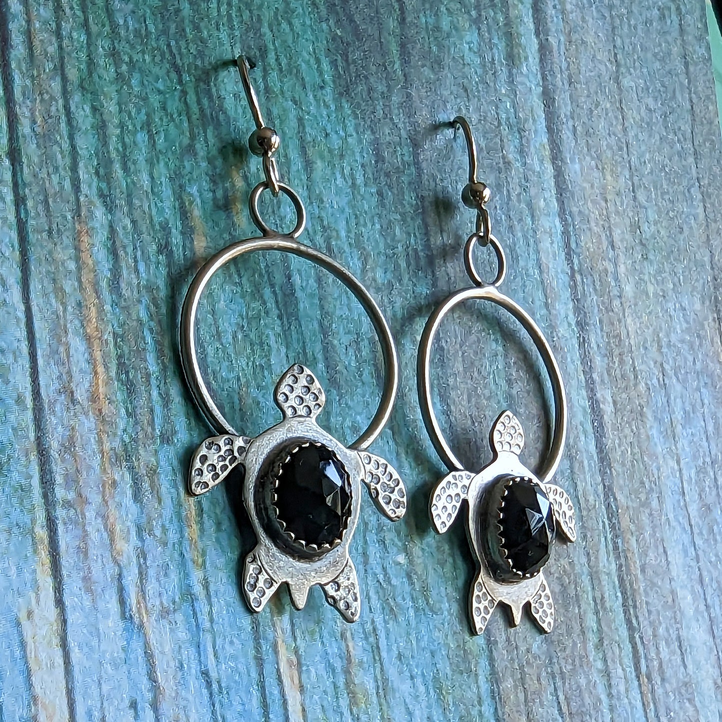 Sterling silver handmade earrings with rosecut black onyx on blue background