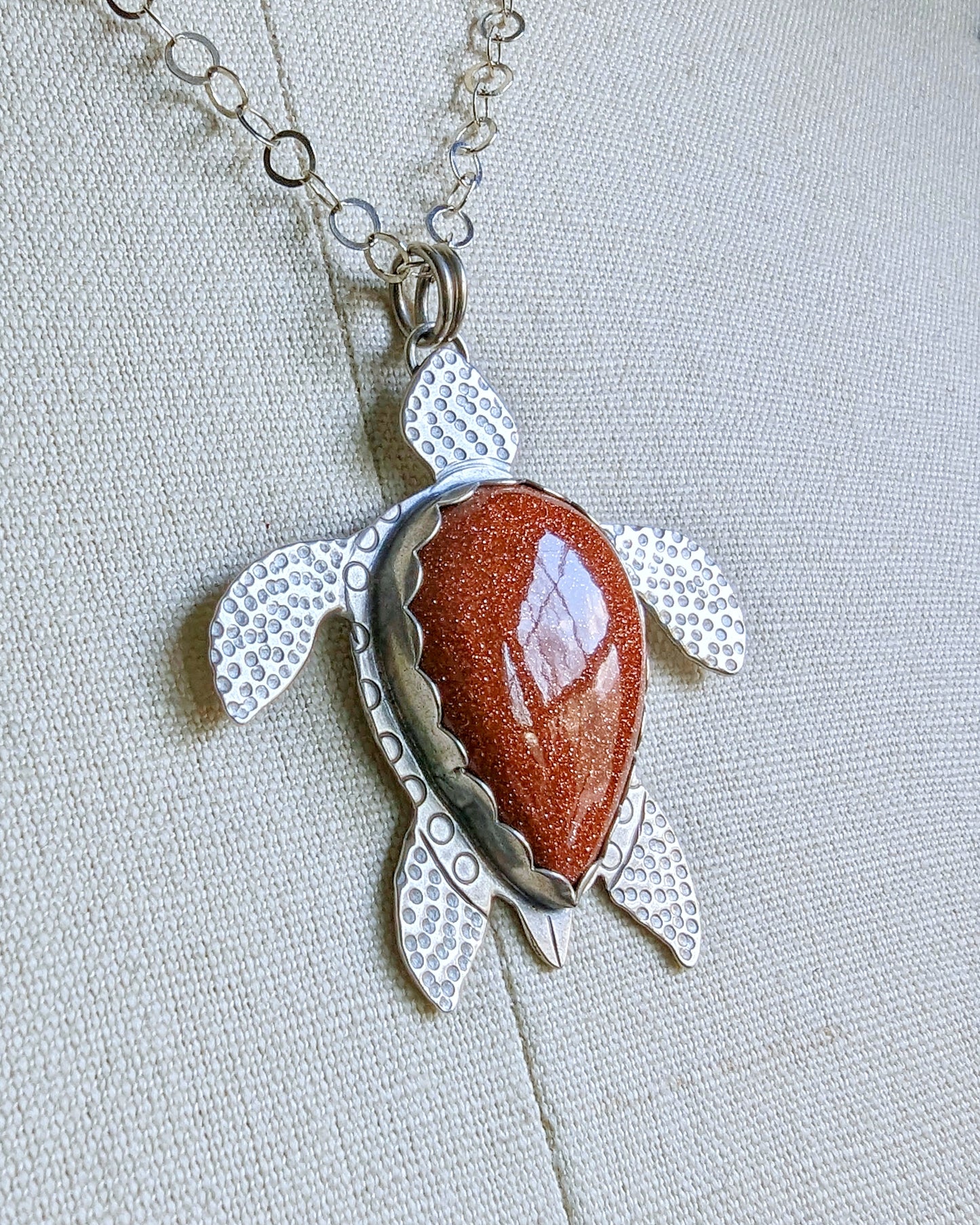 Sterling silver handmade sea turtle necklace with goldstone on an angle shot