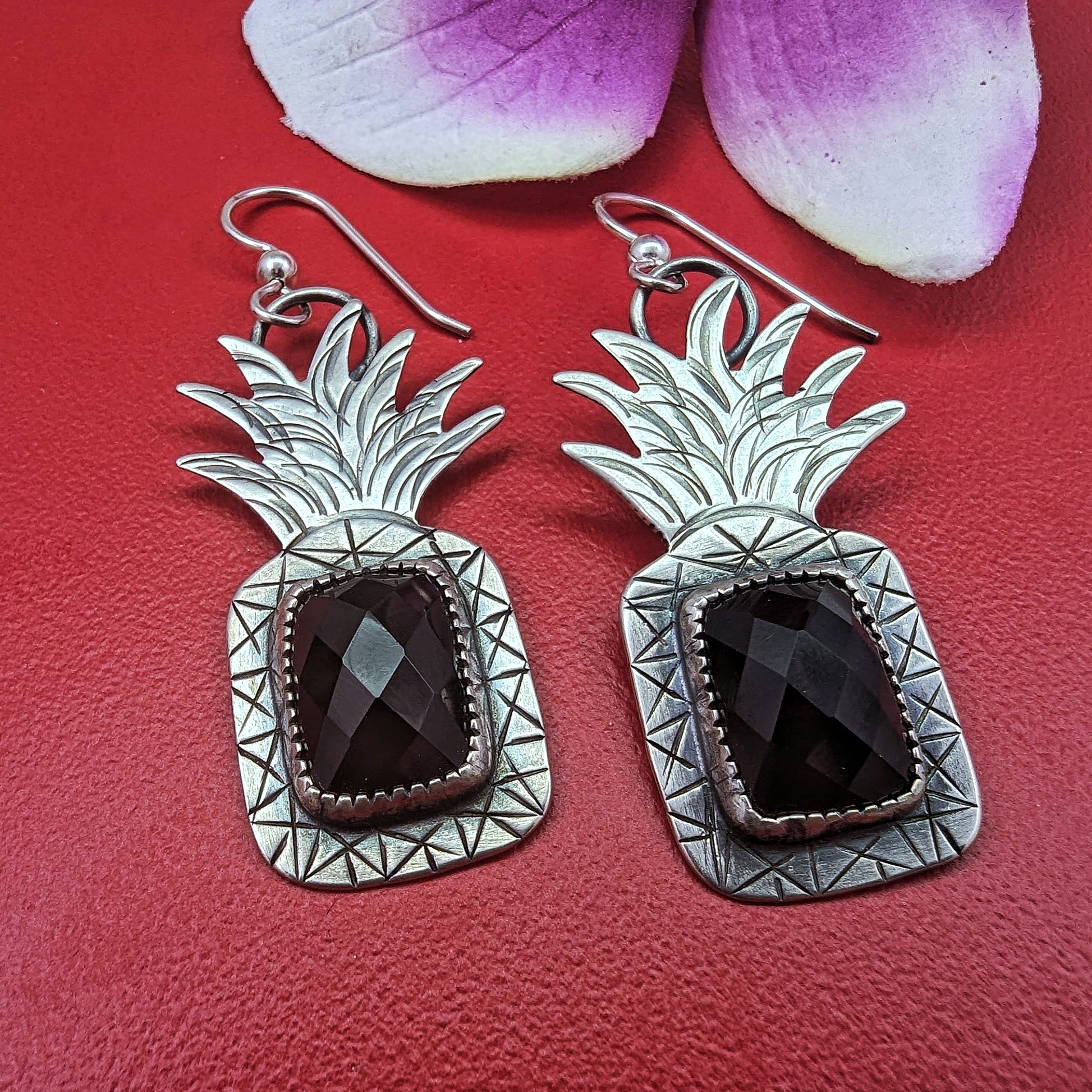 Sterling silver pineapple earrings with rectangular rosecut black onyx on red background