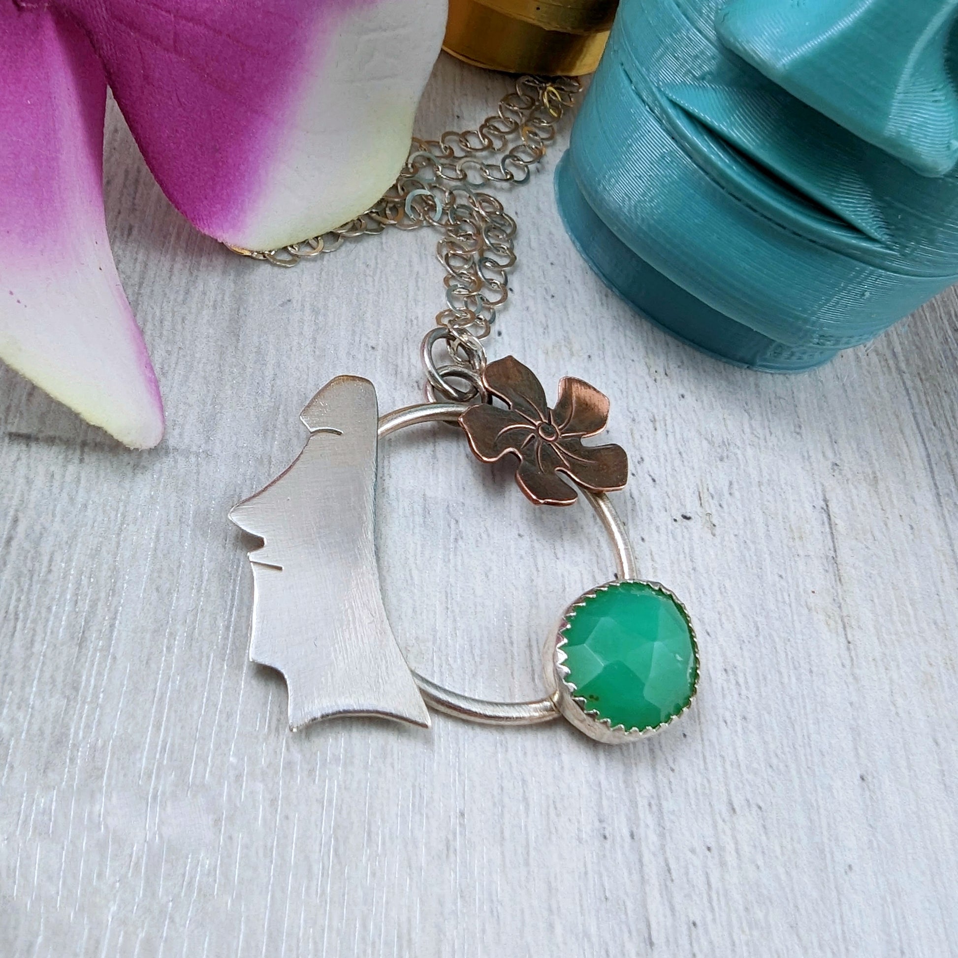 Sterling silver, copper, and chrysoprase necklace on light background with flowers