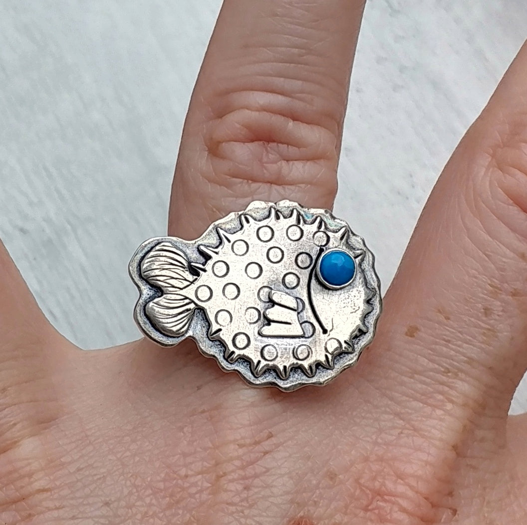 Pufferfish ring with blue howlite eye shown on ring finger