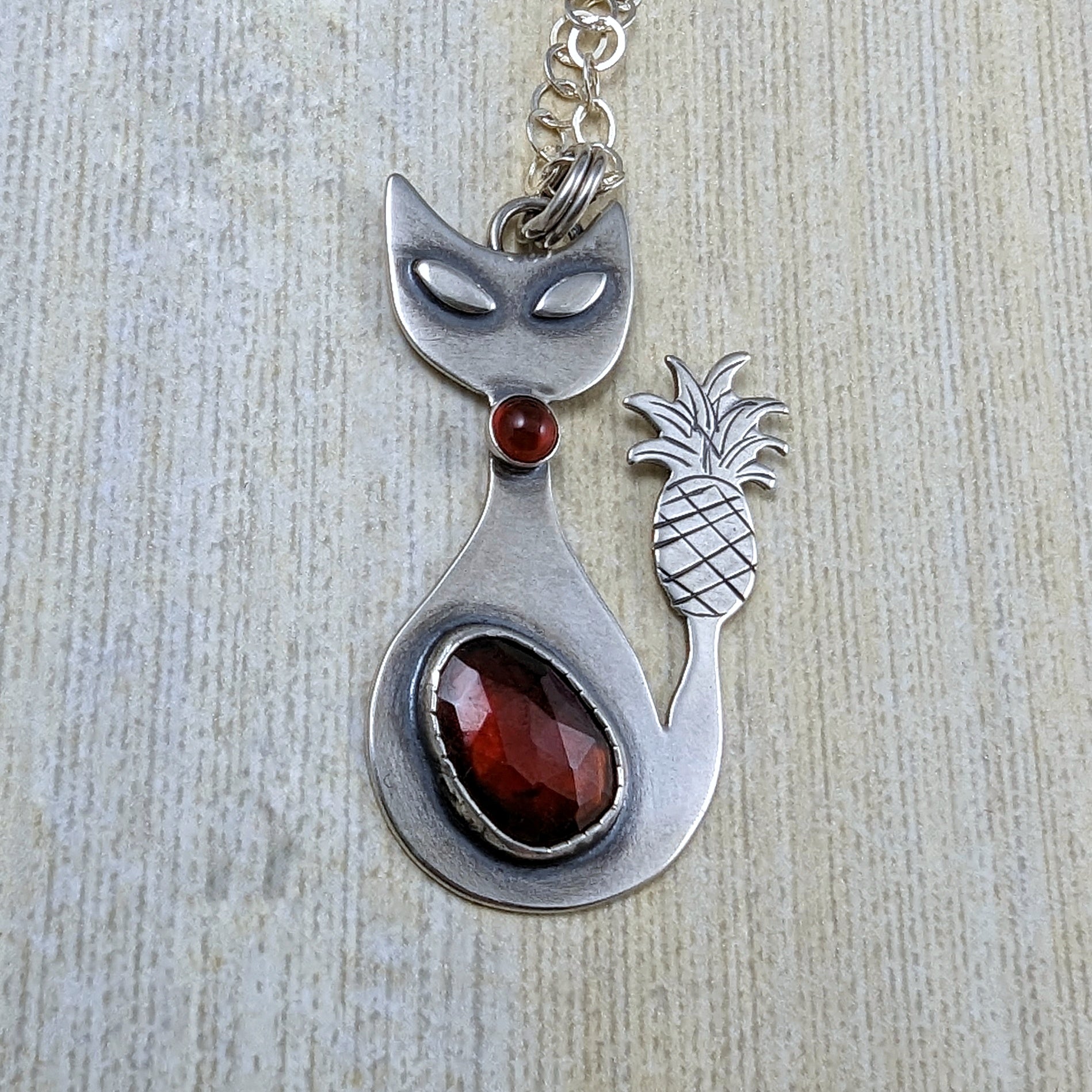 Sterling silver handmade cat with pineapple tail and garnet close up shot