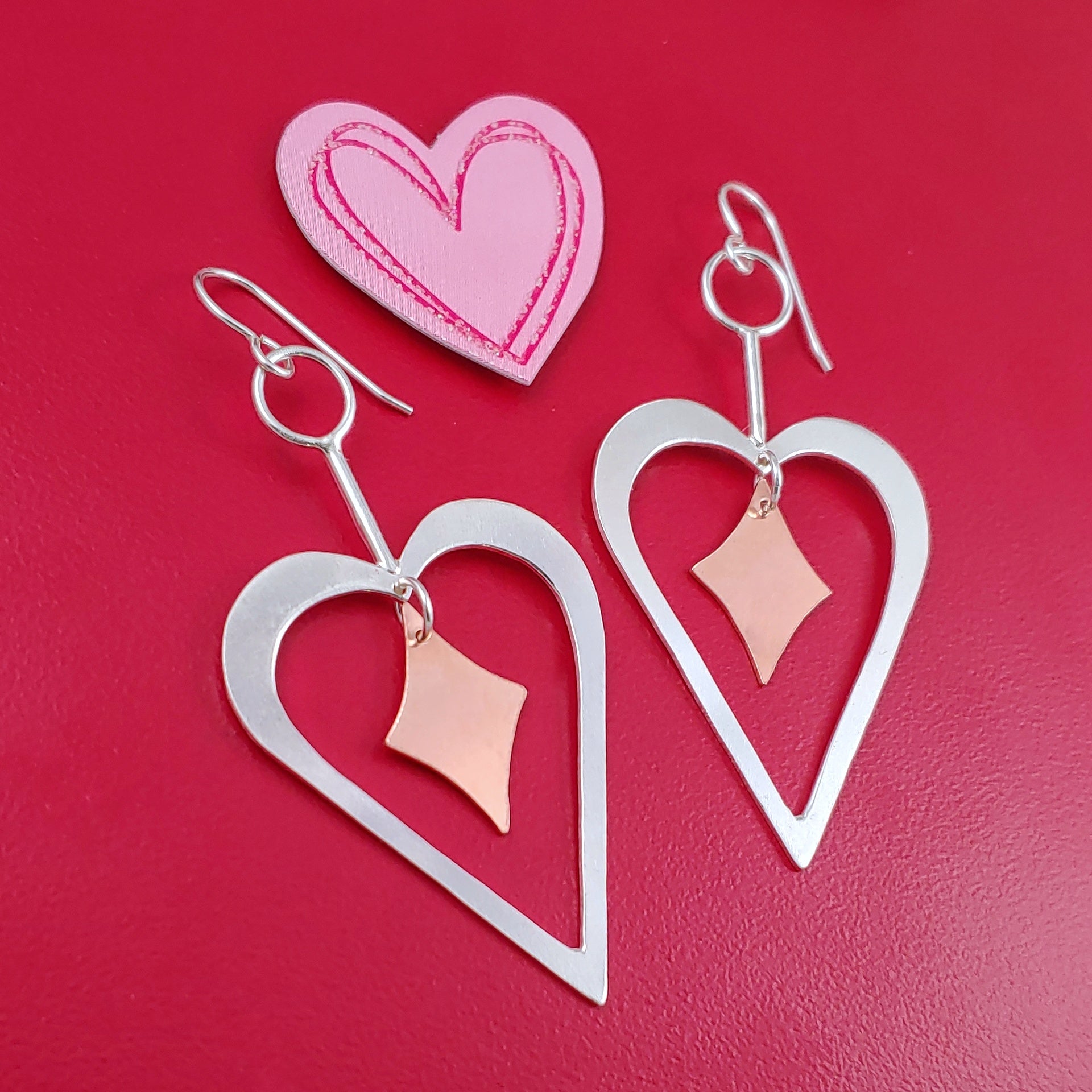 Handmade Sterling silver heart shaped earrings with copper retro diamonds dangling from the center