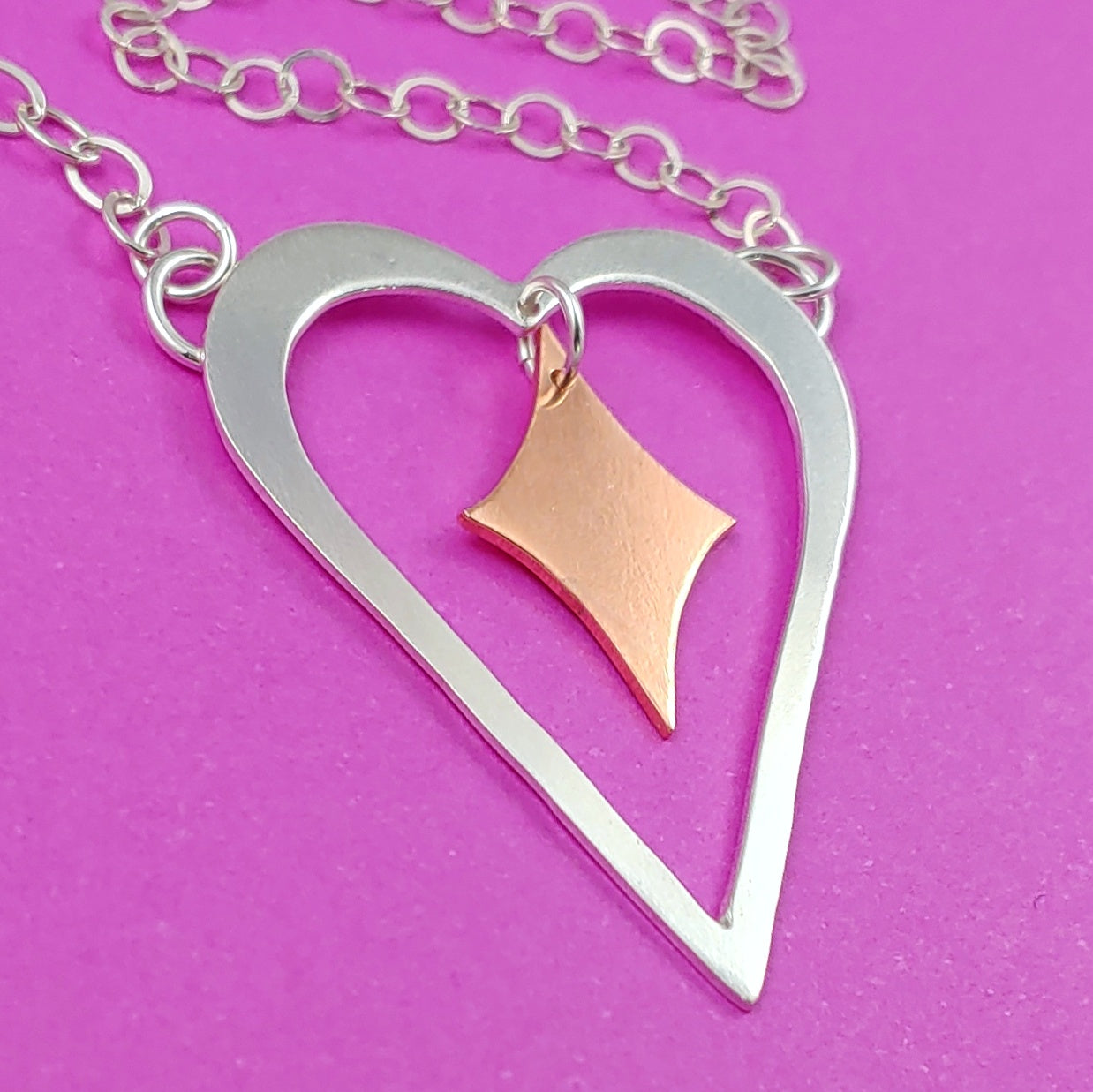 Heart shaped sterling silver necklace with a copper retro diamond dangling from the center