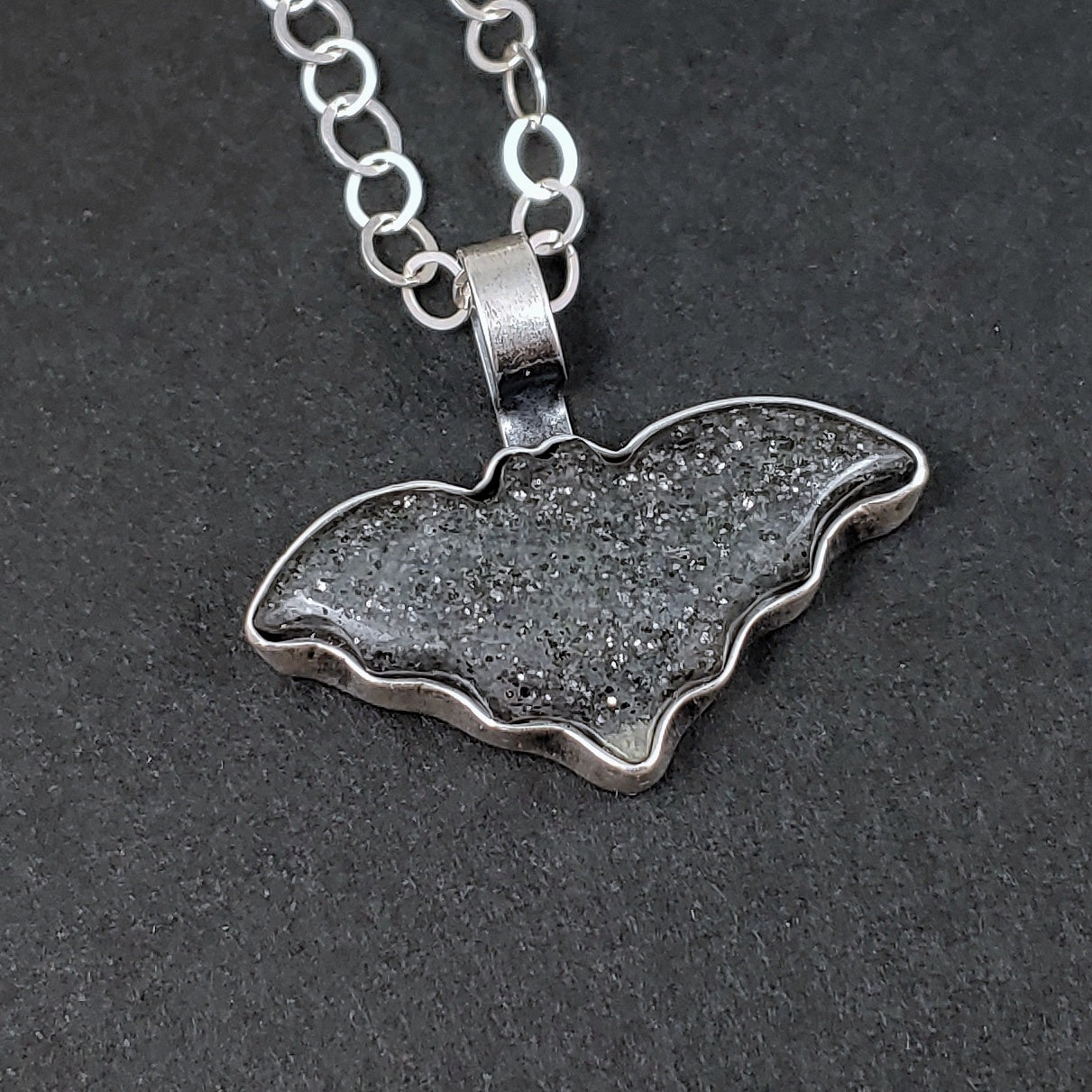Midnight quartzite bat necklace on a black background.