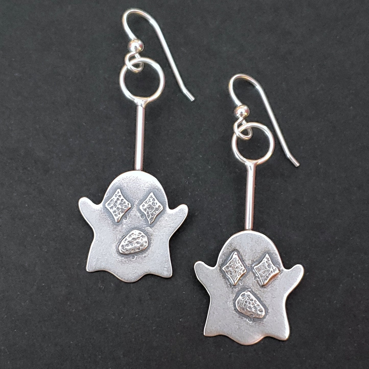 Cute sterling silver ghost earrings with retro diamond eyes on a black background.