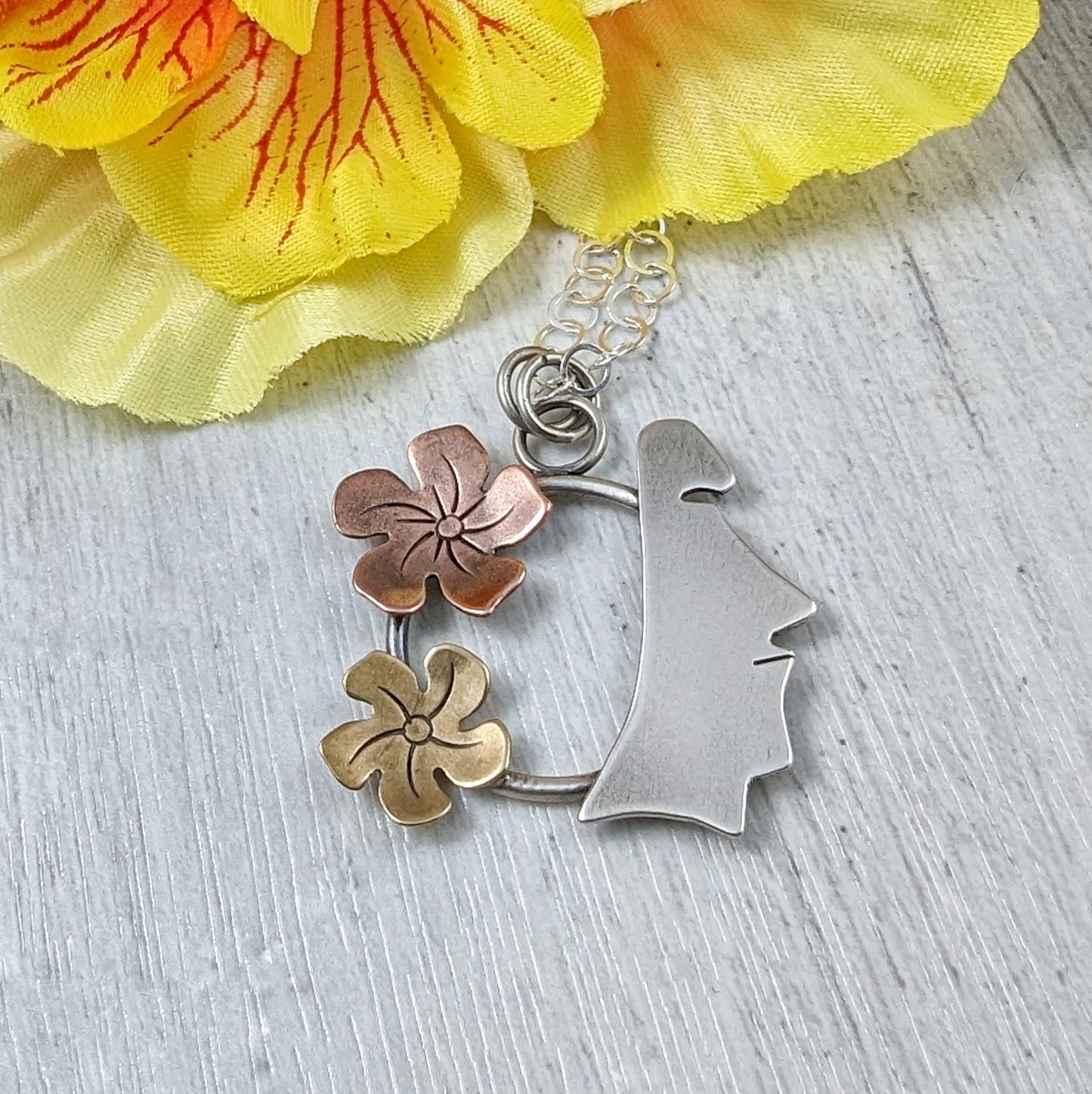 Sterling silver, copper, and brass necklace on a background with flowers