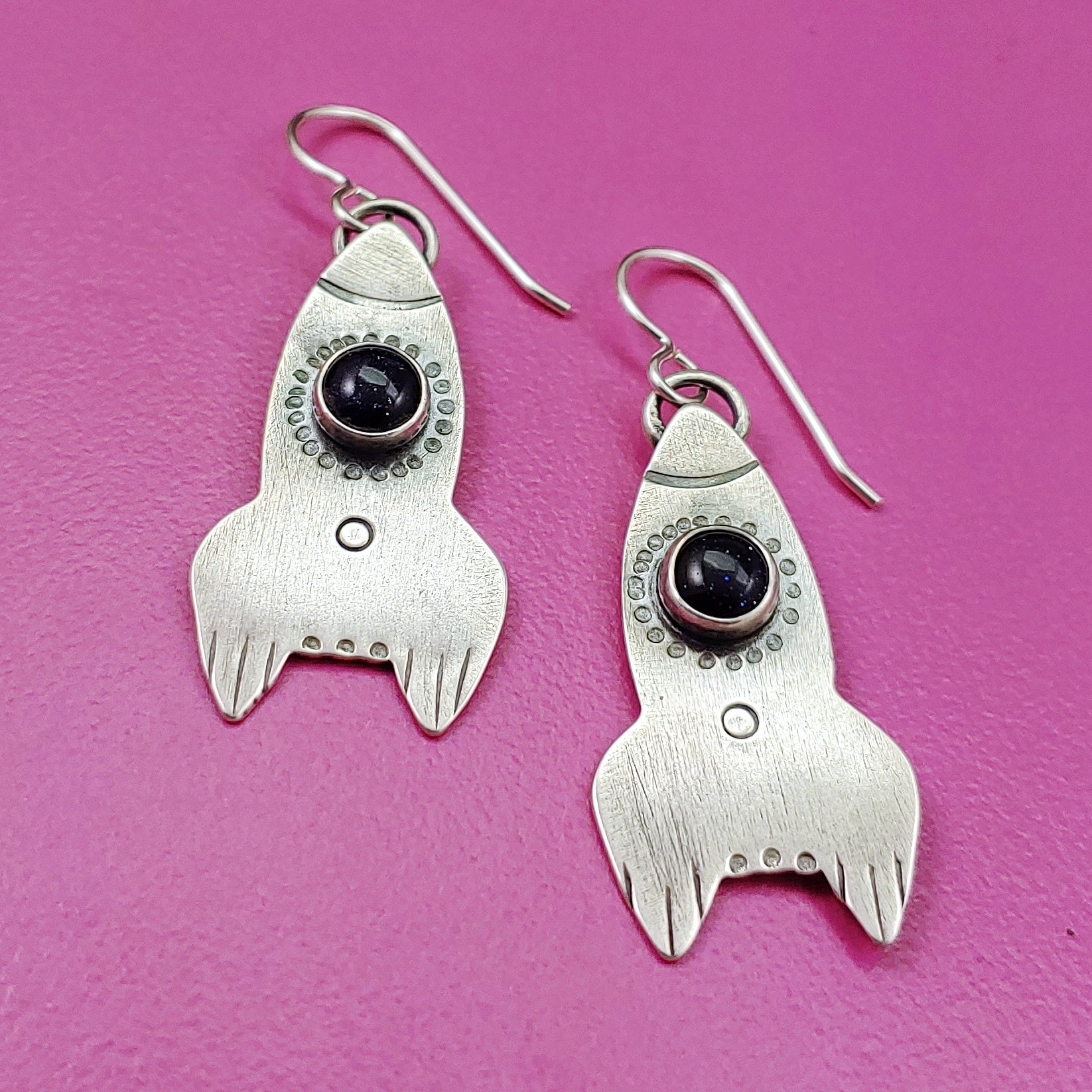 Rocket ship earrings in sterling silver on pink bacground
