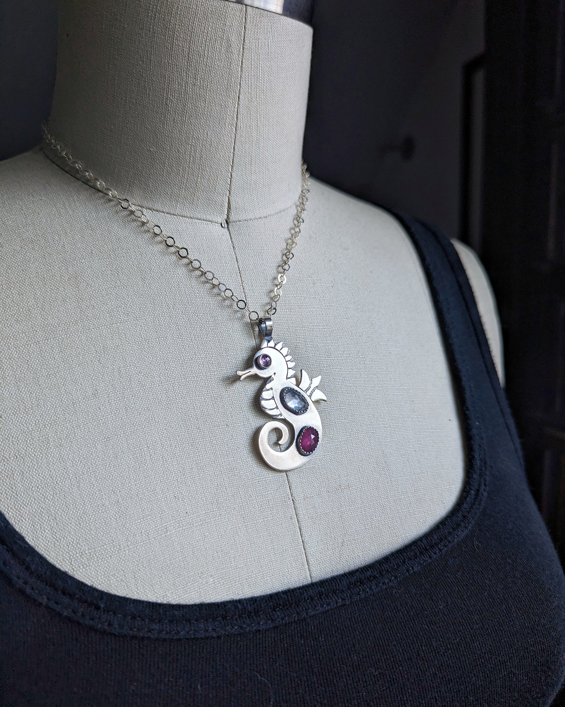 Sterling silver handmade seahorse with rosecut danburite and ruby with pink cubic zirconia eye on dress form at a diagonal