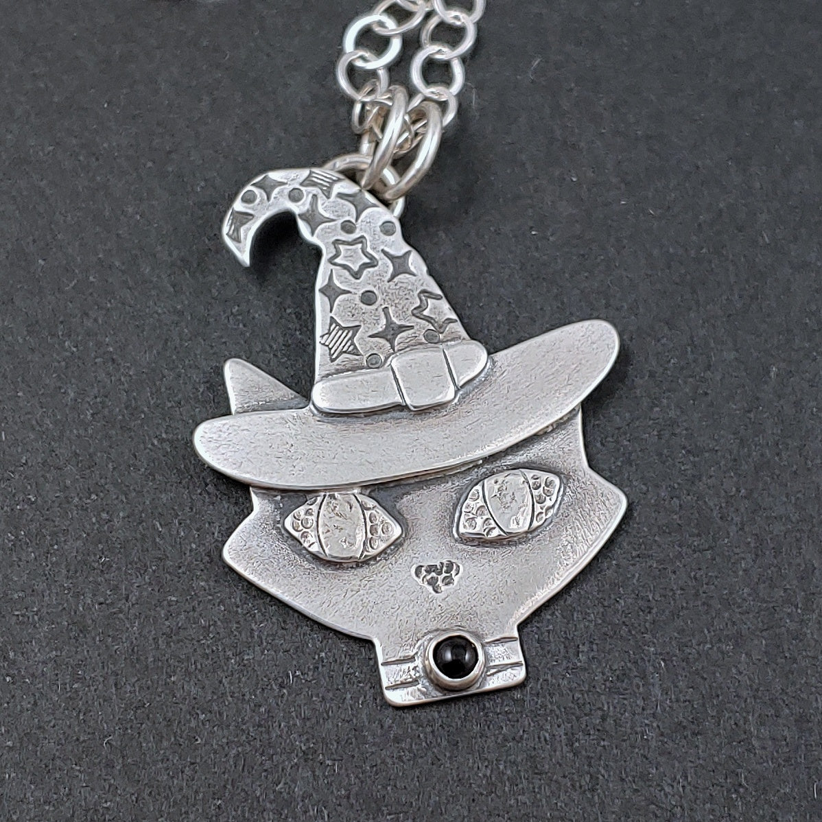 Sterling silver mid mod cat head with a wizard hat on black background.