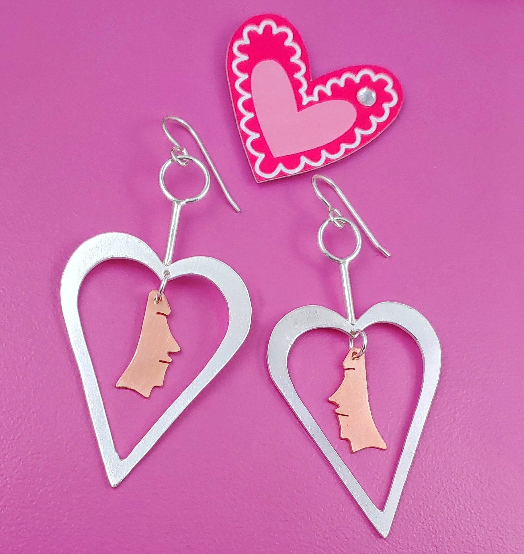 Sterling silver heart shaped earrings with copper necklace dangling from the centers 
